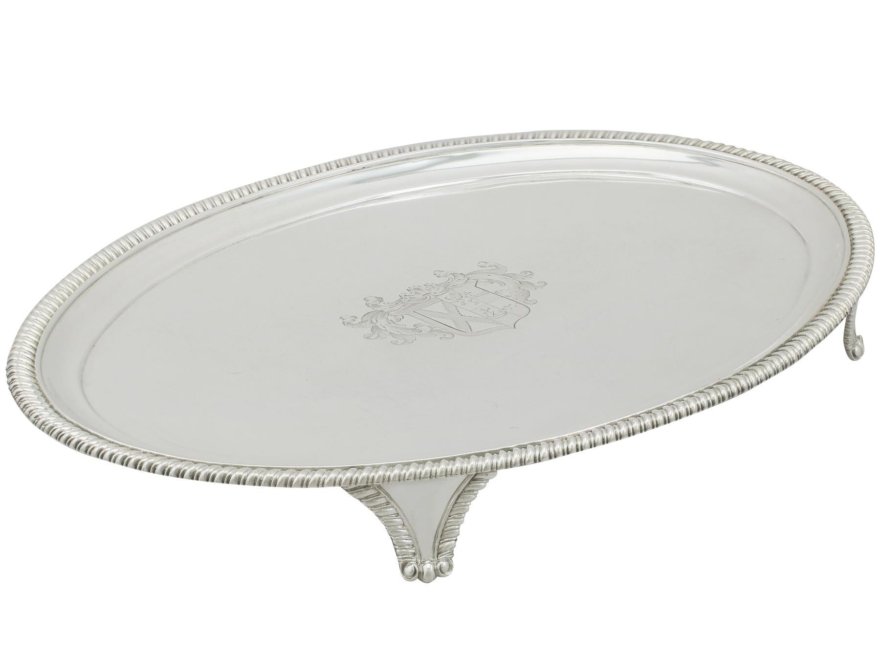 This fine antique George IV sterling silver salver has a plain oval, classic English form.


The surface of the salver is embellished with a fine and impressive contemporary bright cut engraved coat of arms with impressive scrolling leaf