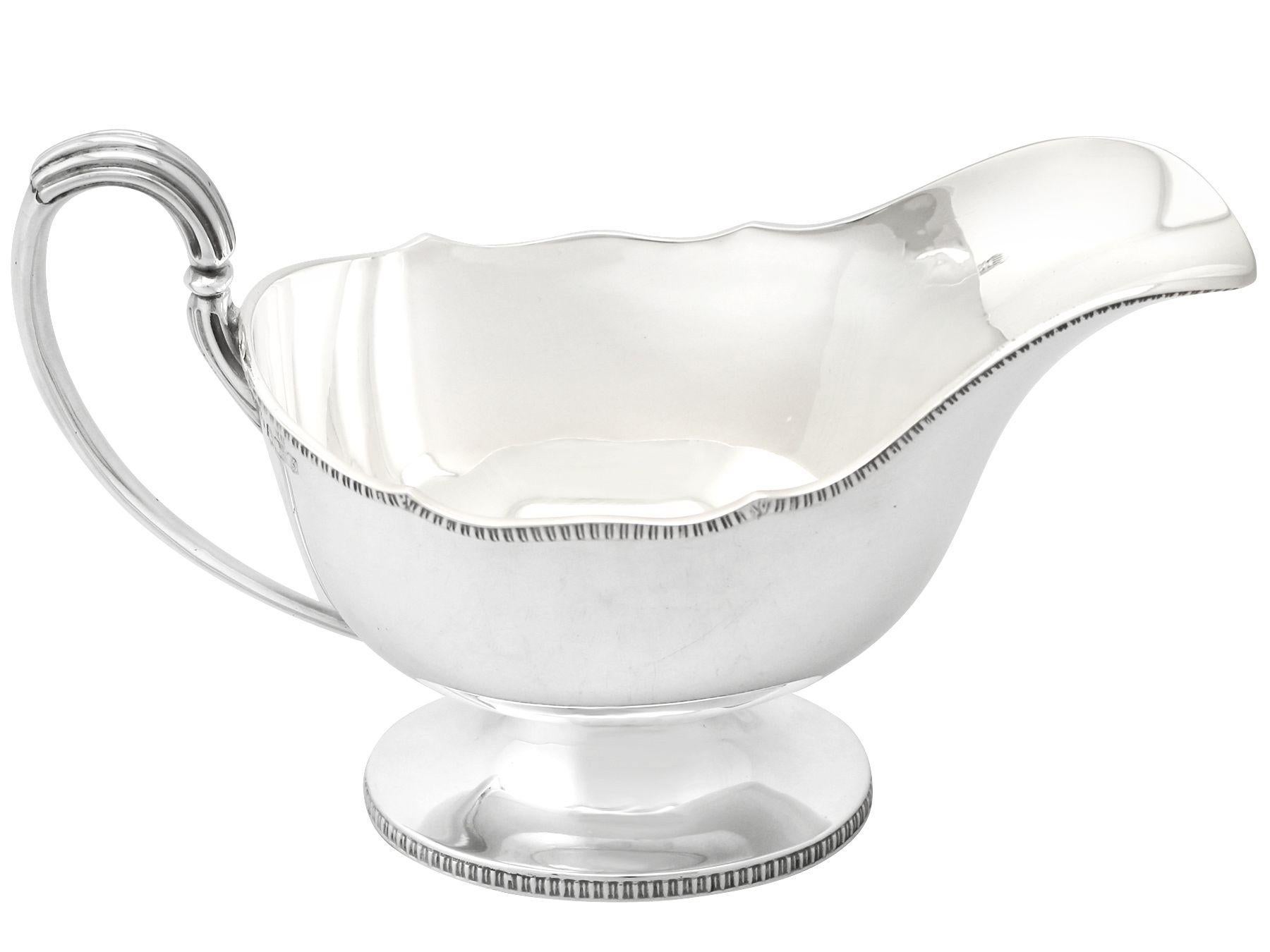 A fine and impressive antique George V English sterling silver sauceboat; an addition to our silver dining collection.

This fine antique George V sterling silver sauceboat/gravy boat has an oval plain boat shaped form onto an oval spreading
