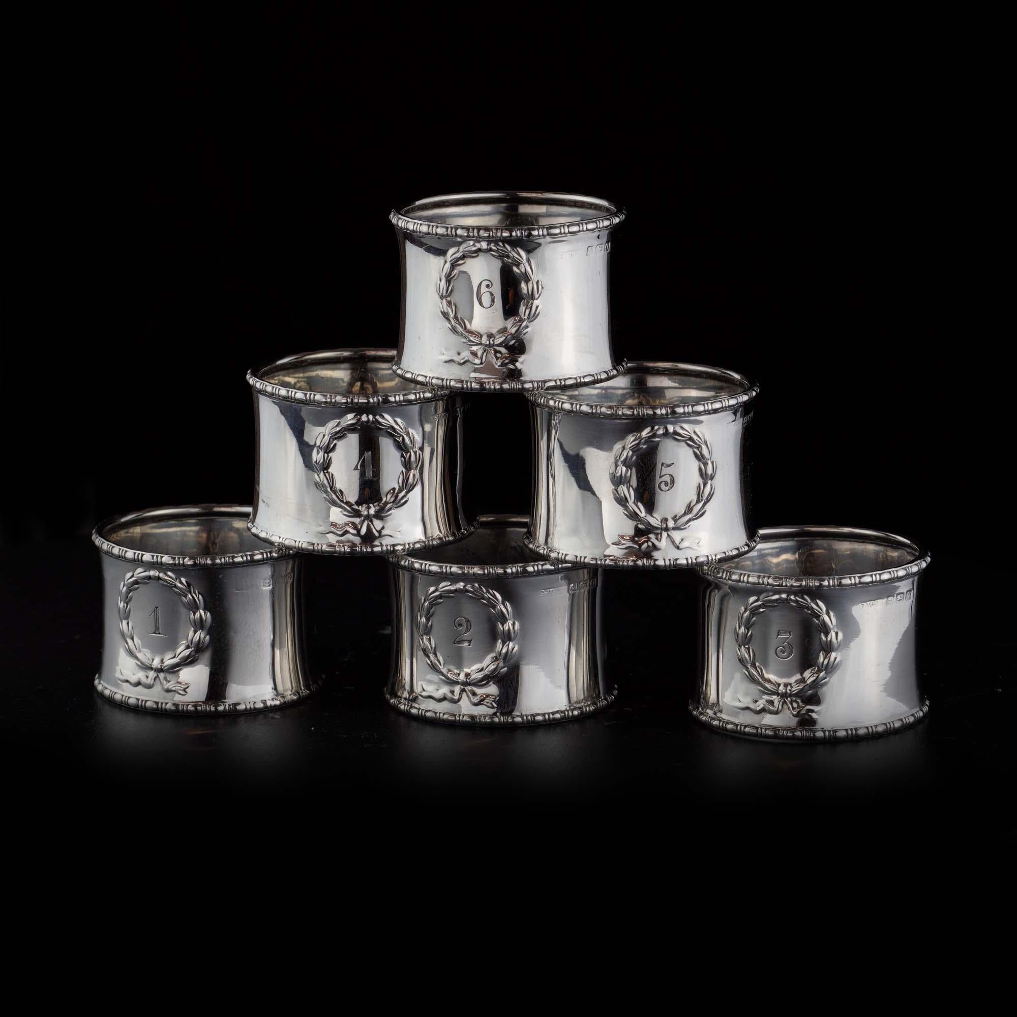 Antique sterling silver set of 6 napkin rings, decorated and engraved with wreaths and ribbons, with numbers at the centre from 1 to 6. 

They're not just for decoration! These are the perfect way to keep your tablecloth from slipping off of the