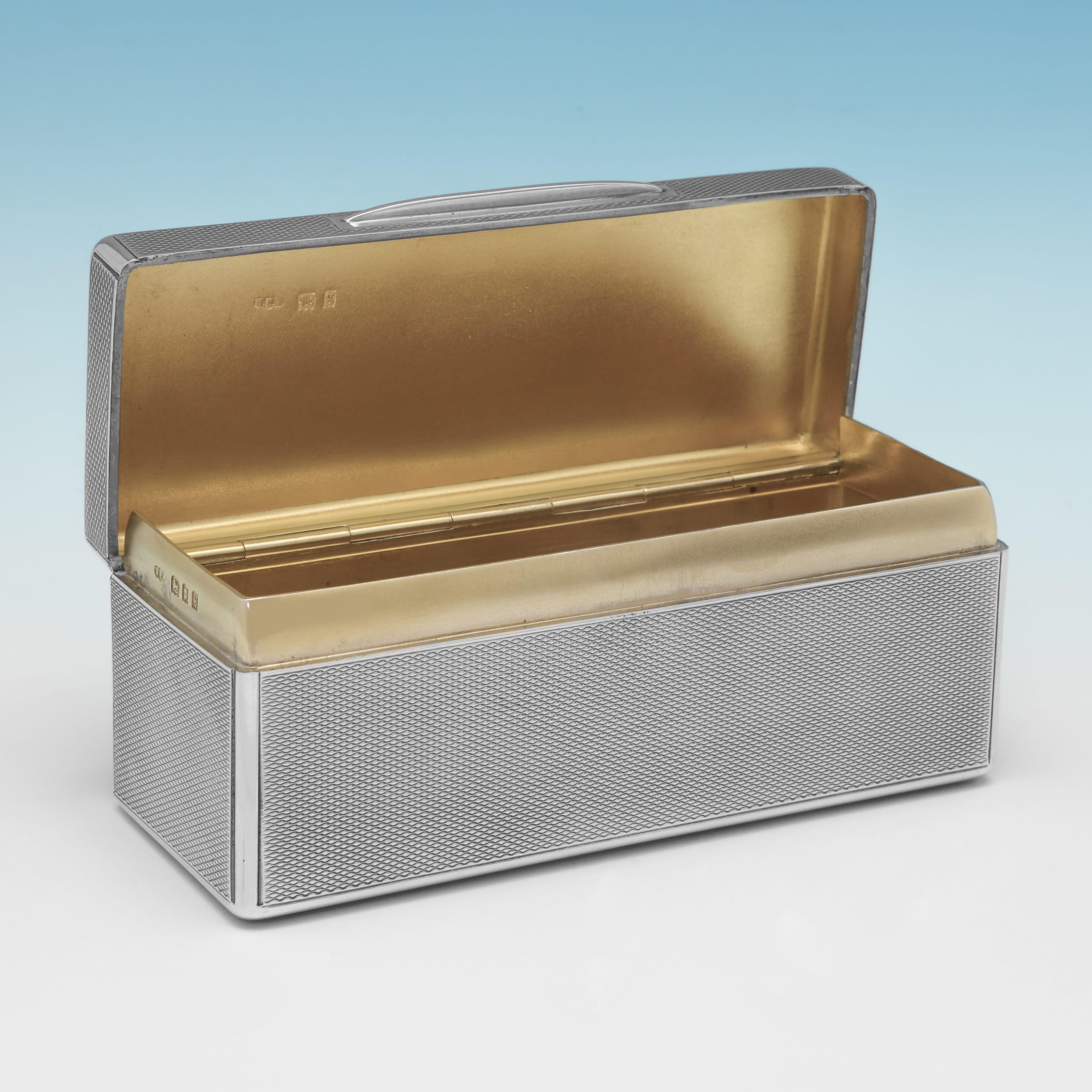 Poinçonnée à Londres en 1922 par Wright & Davies, cette tabatière ancienne en argent sterling d'époque George V est de forme rectangulaire et présente un décor guilloché à l'extérieur et un intérieur doré. La tabatière mesure 4,5 cm de haut, 11,5 cm