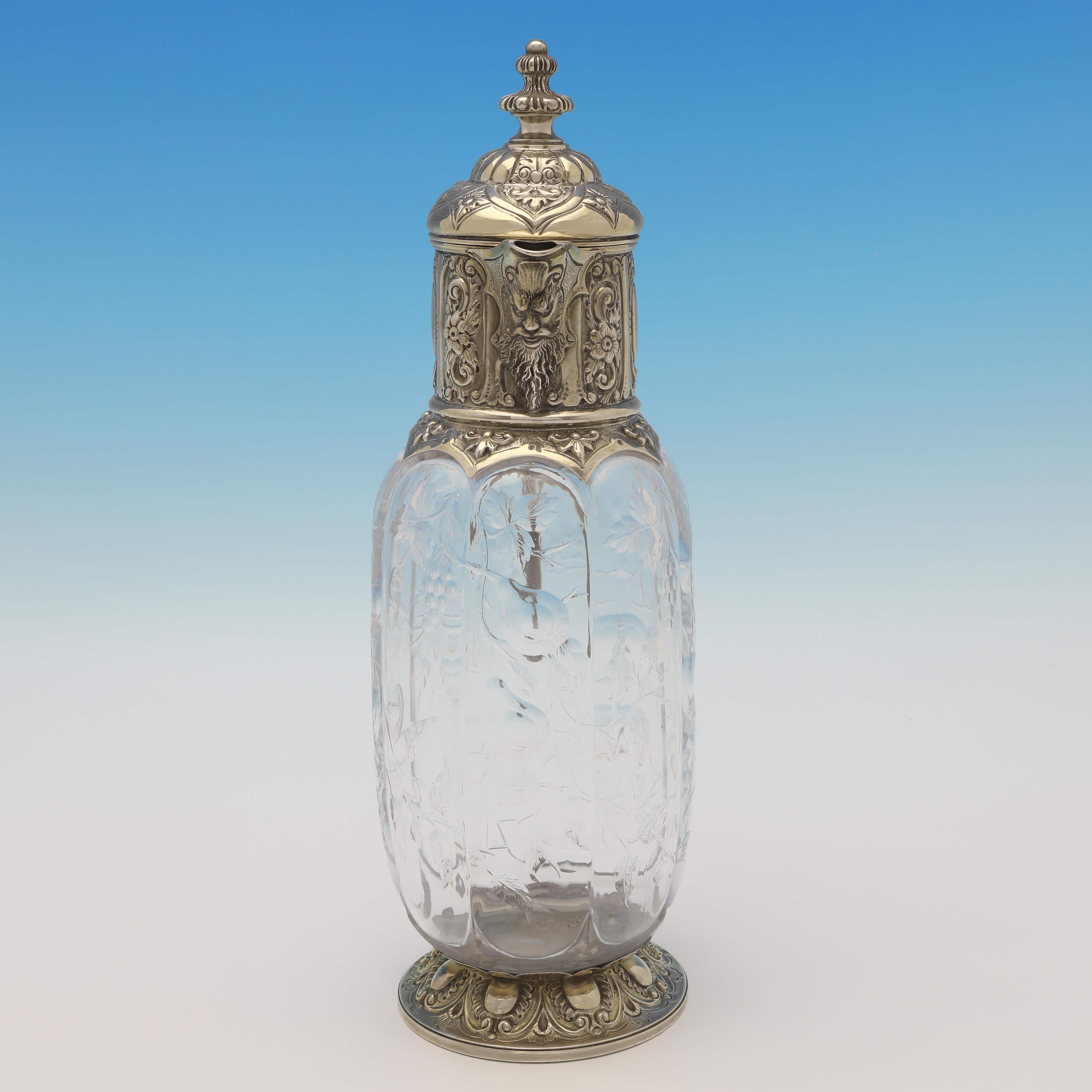 Hallmarked in London in 1891 by Charles Edwards, this stunning, Victorian, Antique Sterling Silver Claret Jug, features an etched glass body likely designed by Thomas Webb, and an ornate gilt silver mount and foot. The claret jug measures