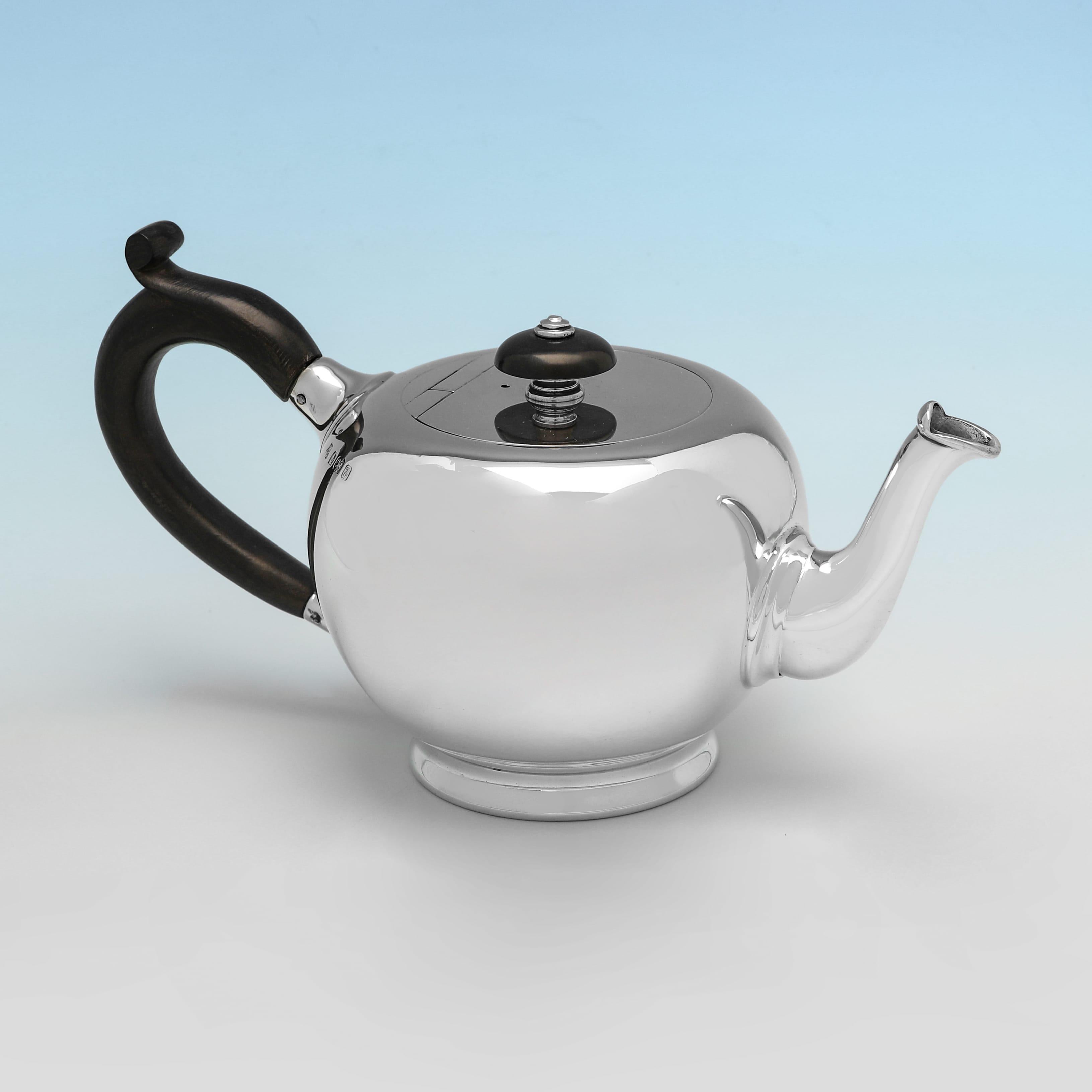 Poinçonnée à Birmingham en 1924 par S.W. Smith & Co, cette belle théière ancienne en argent sterling d'époque George V est en forme d'ogive, de style sobre, avec une charnière affleurante, une poignée en bois et un embout. La théière mesure 10 cm de