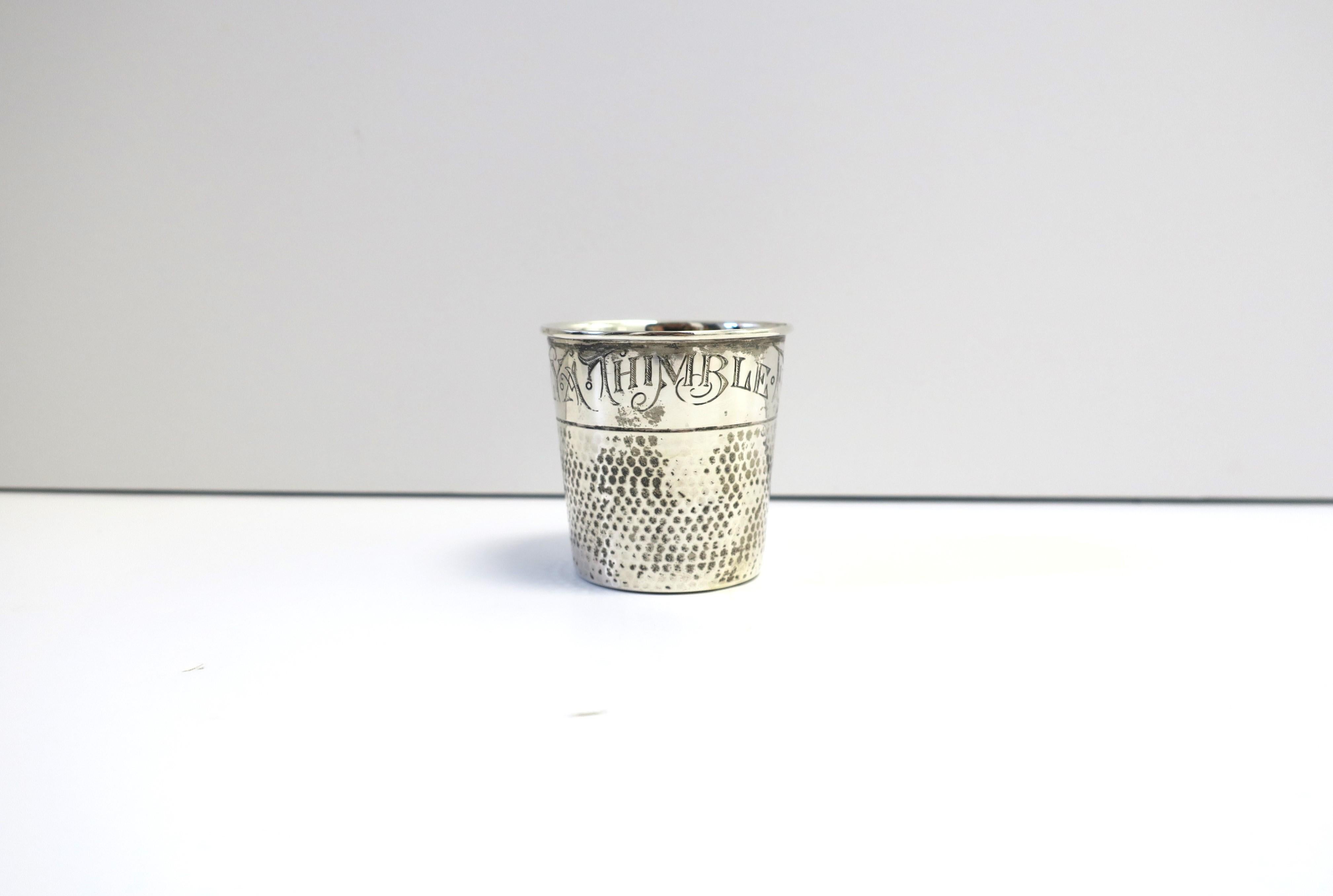 A sterling silver 'thimble' jigger shot glass, Art Nouveau period, by E.G. Webster & Sons, circa late-19th century, USA. Piece, in the shape of the thimble, and of the Art Nouveau period, with engraving, a play on the expression, ‘Just a Thimble
