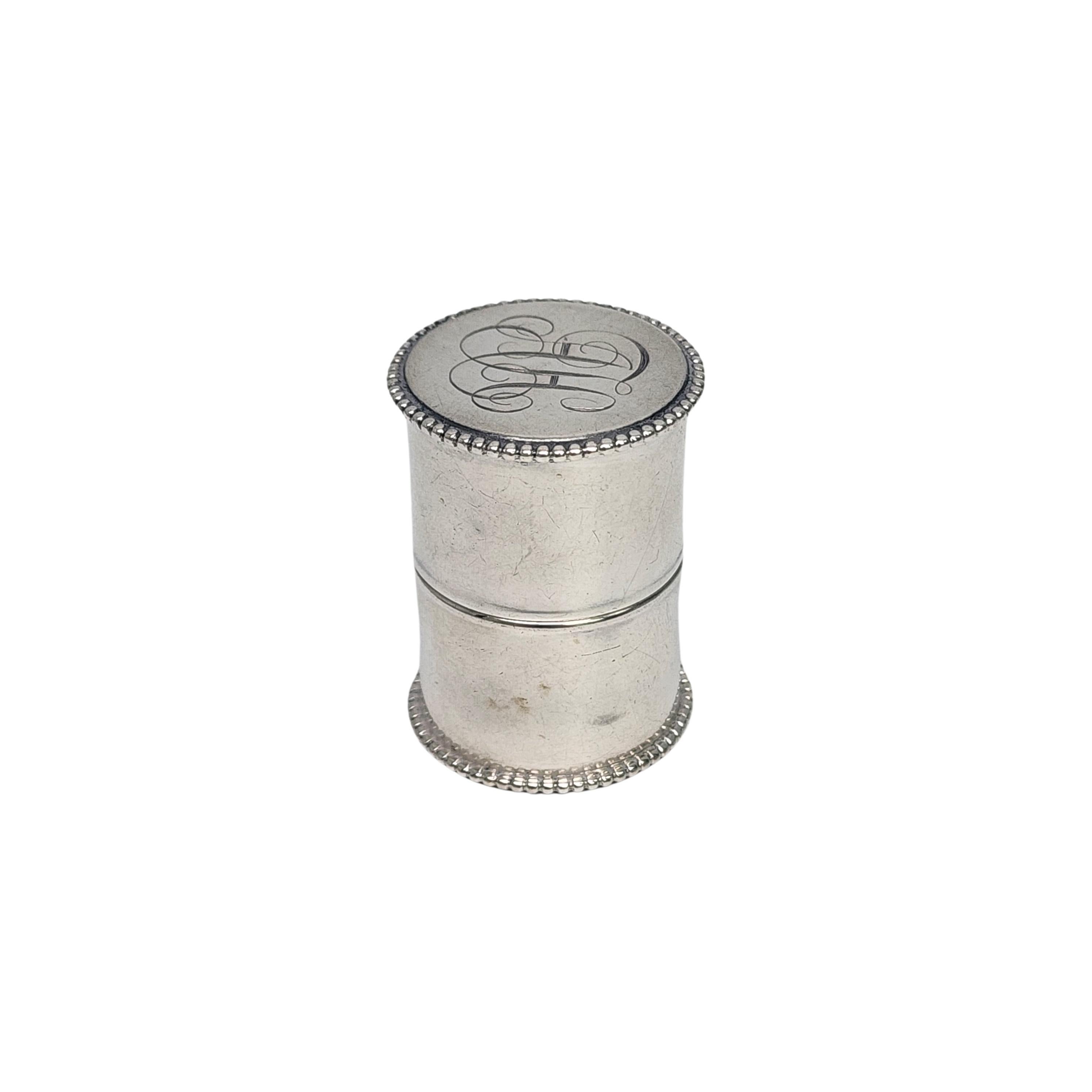 Antique sterling silver thread case with monogram.

Monogram appears to be AH

This cylindrical case holds a spool of thread and dispenses it through a slit with a small opening for the thread. The edges have a beaded edge, the monogram is on the
