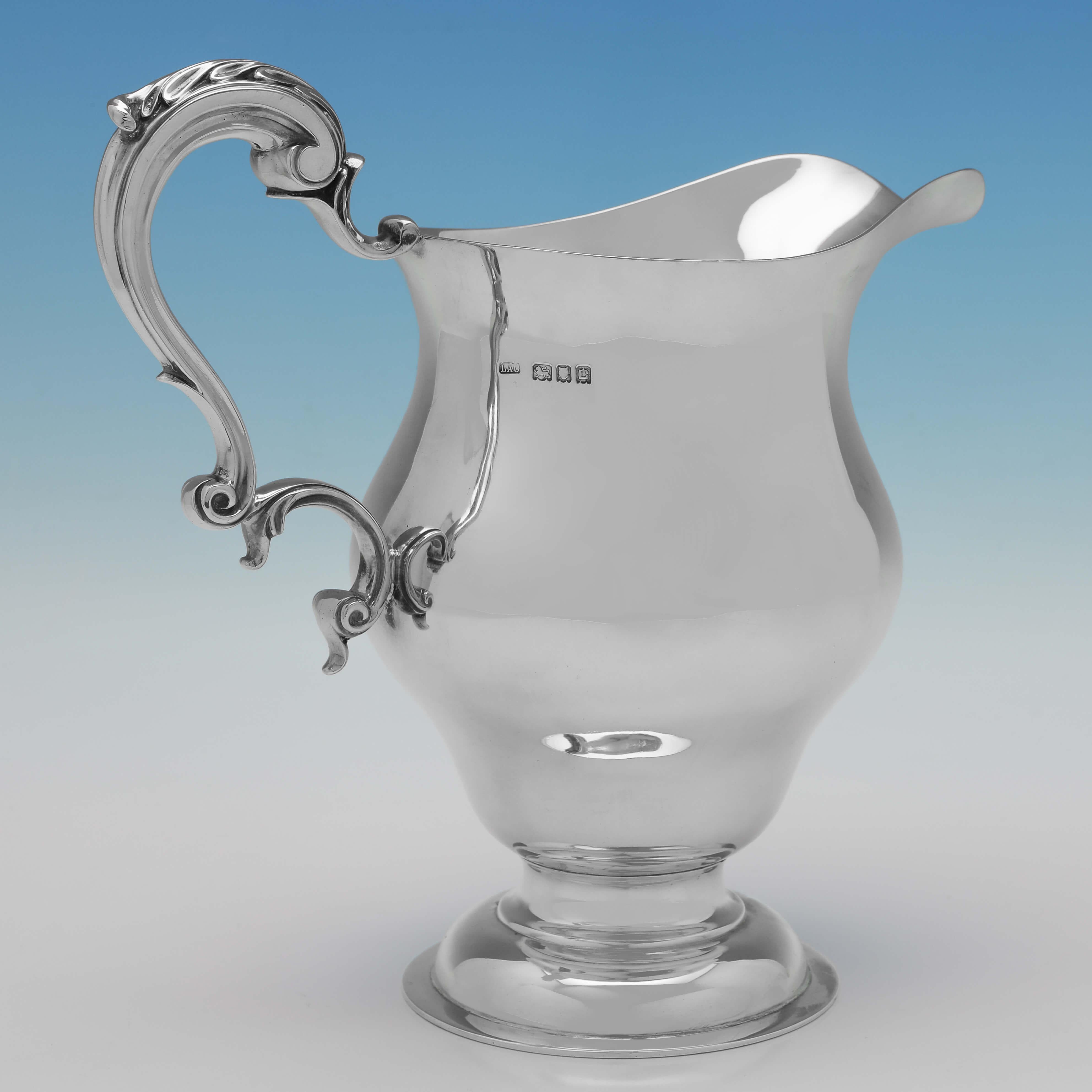 Hallmarked in London in 1918 by L. A. Crichton, this handsome, Antique Sterling Silver Water Jug, is plain in style and features an acanthus detailed scroll handle. 

The water jug measures 9.25