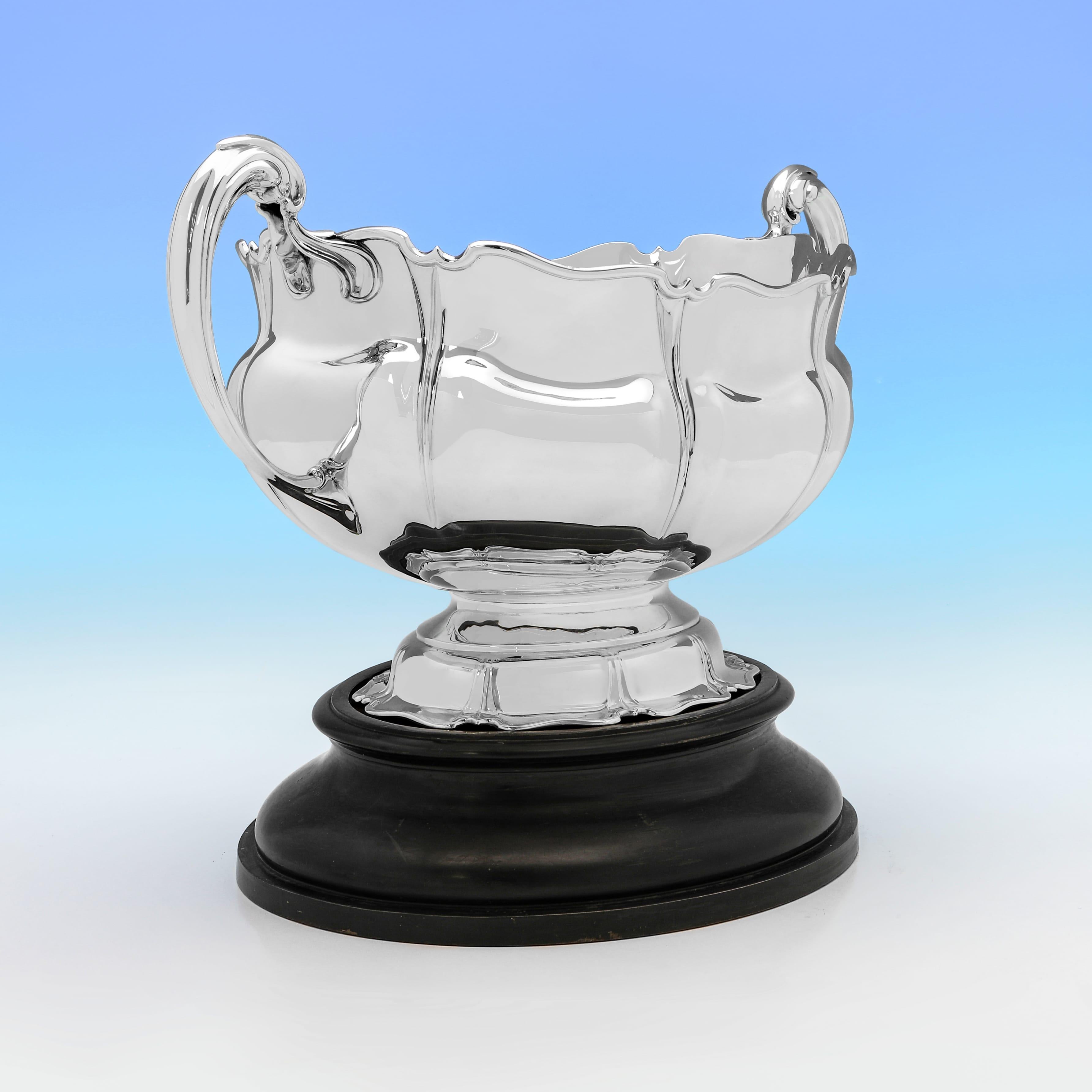 Con marchio a Sheffield nel 1910 da Atkin Brothers, questa attraente cisterna per il vino in argento sterling antico del periodo di Giorgio V è di forma ovale e di gusto art nouveau, poggia sul basamento in legno originale e presenta bordi in giunco
