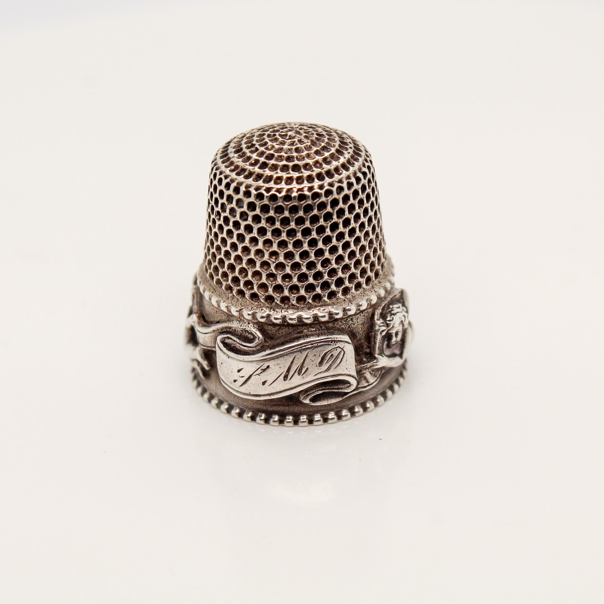 A fine sterling silver 'Cupid Special' thimble.

By Stern Bros & Company. 

Stern Bros & Co. was founded in Philadelphia in 1868 by Nathan Stern and would relocate to New York within a few years of its founding. They functioned out of New York until