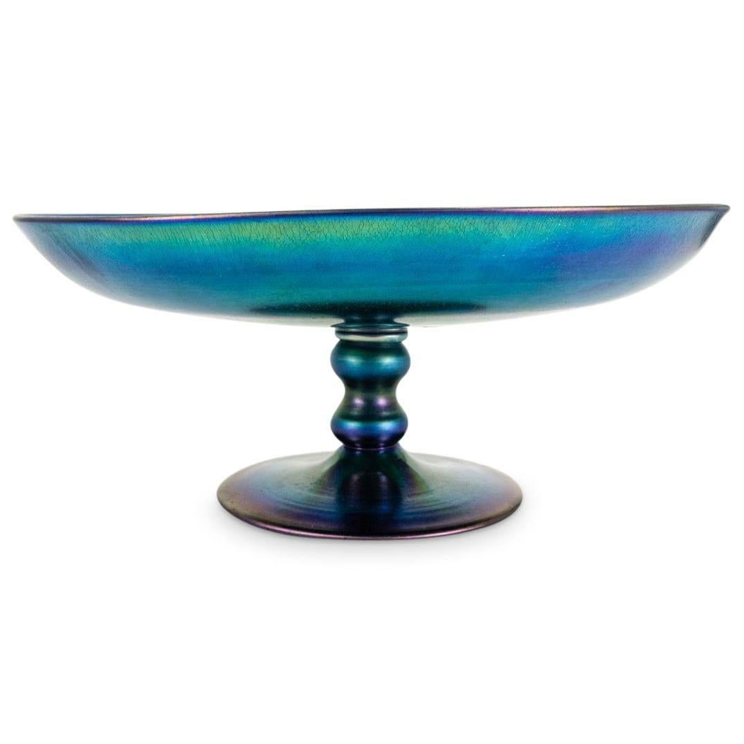 Our beautiful footed centerpiece bowl in iridescent blue Aurene glass dates from the very early 20th century and is in excellent condition, with no losses and some visible scratches.  12 1/2 inch diameter and 5 1/4 inches tall.  Underside with the