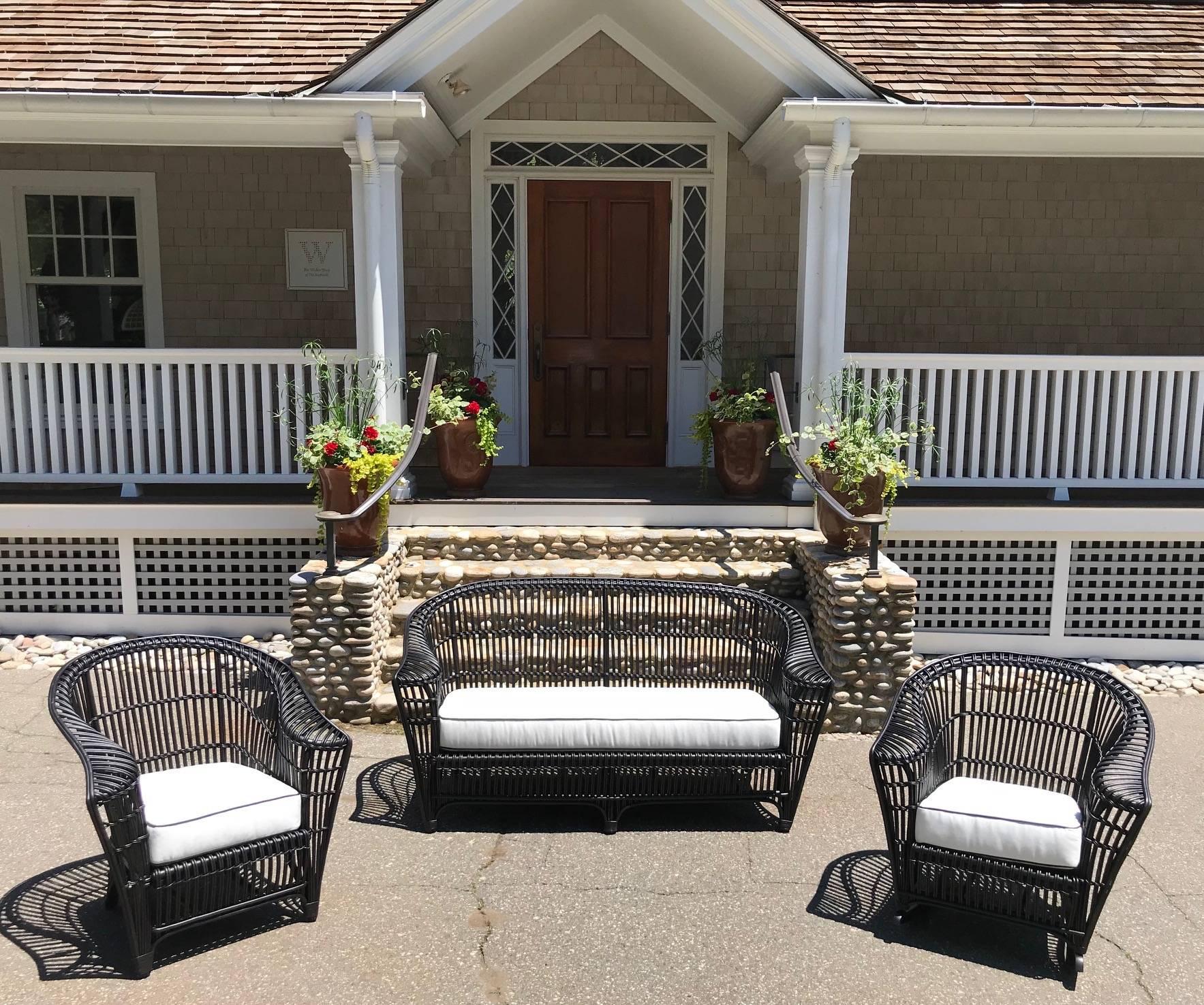 Antique stick rattan porch furniture consisting of a sofa, chair, rocker and sofa table including newly made white sunbrella cushions with black piping. Sofa measures 70