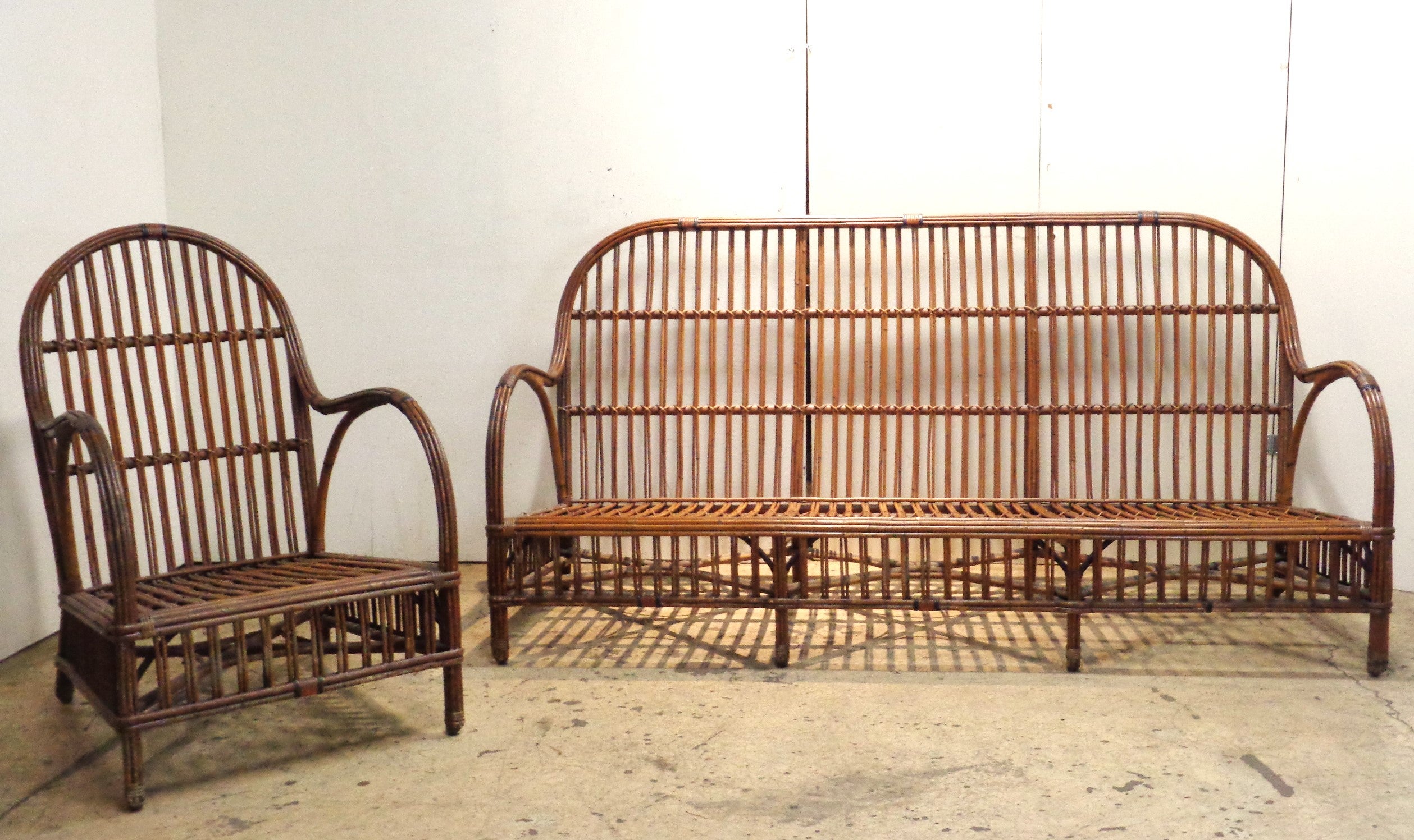 Antique American stick wicker rattan settee w/ matching armchair in beautifully aged original rich natural finish. Great looking set w/ exceptionally fine quality construction. Circa 1930. Settee measures 72 1/2