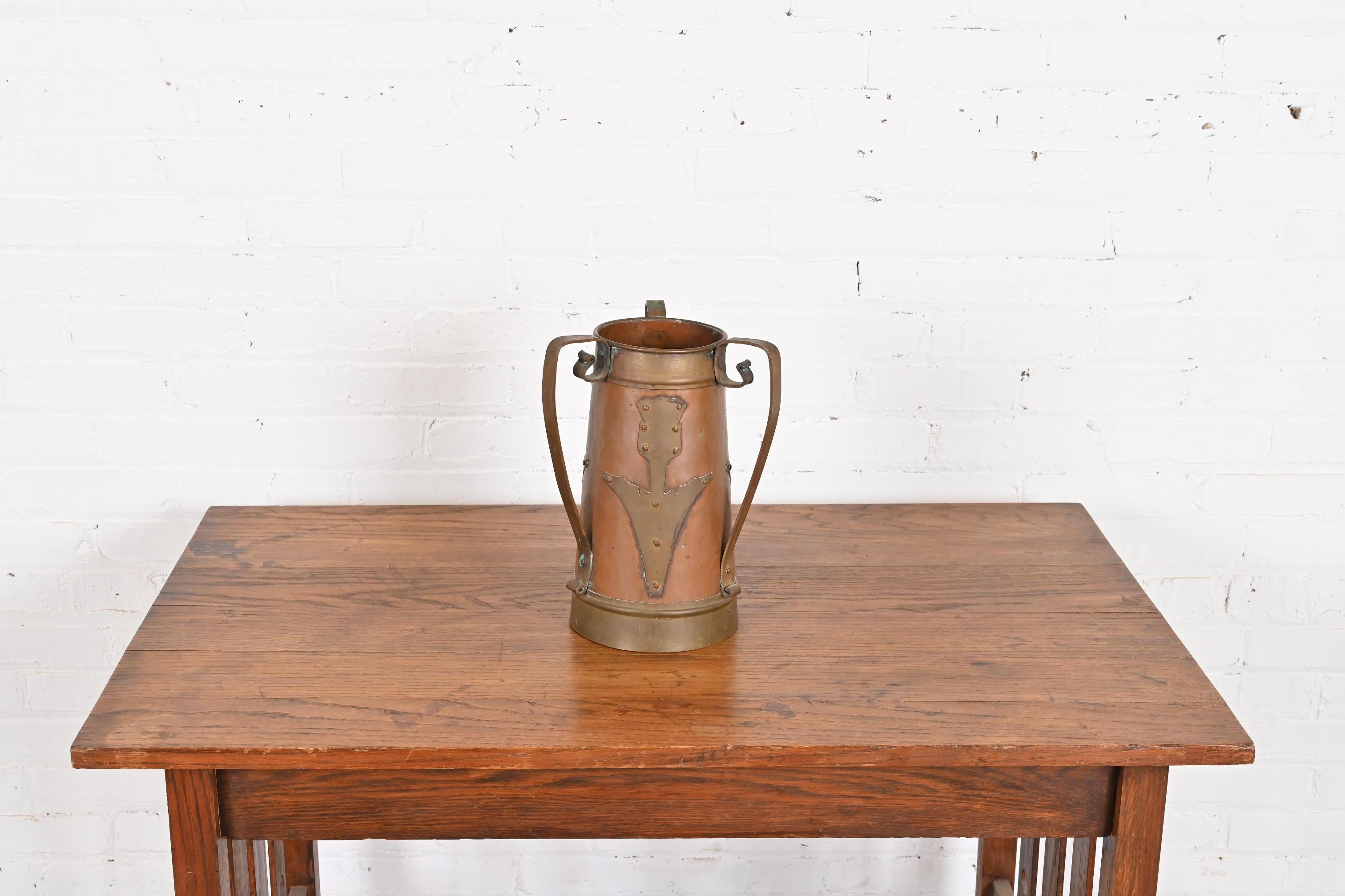Magnifique vase russe à trois anses en cuivre martelé et laiton avec des fleurs stylisées appliquées, d'époque Arts & Crafts.

Importé et vendu par Stickley Brothers

Vers 1903

Dimensions : 9 