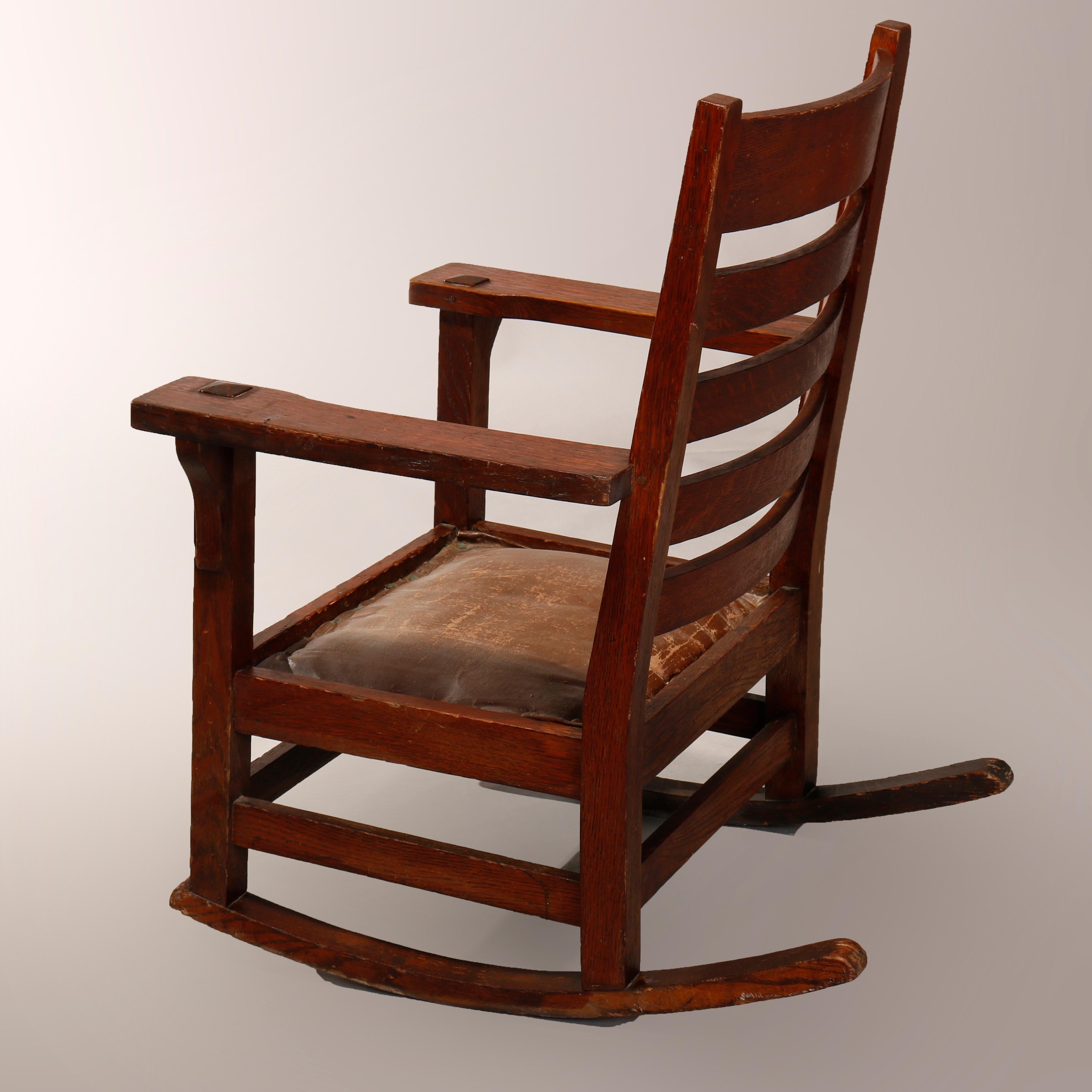An antique Arts & Crafts Mission rocker in the manner of Gustav Stickley offers oak construction with slat back, circa 1910.

Measures: 35