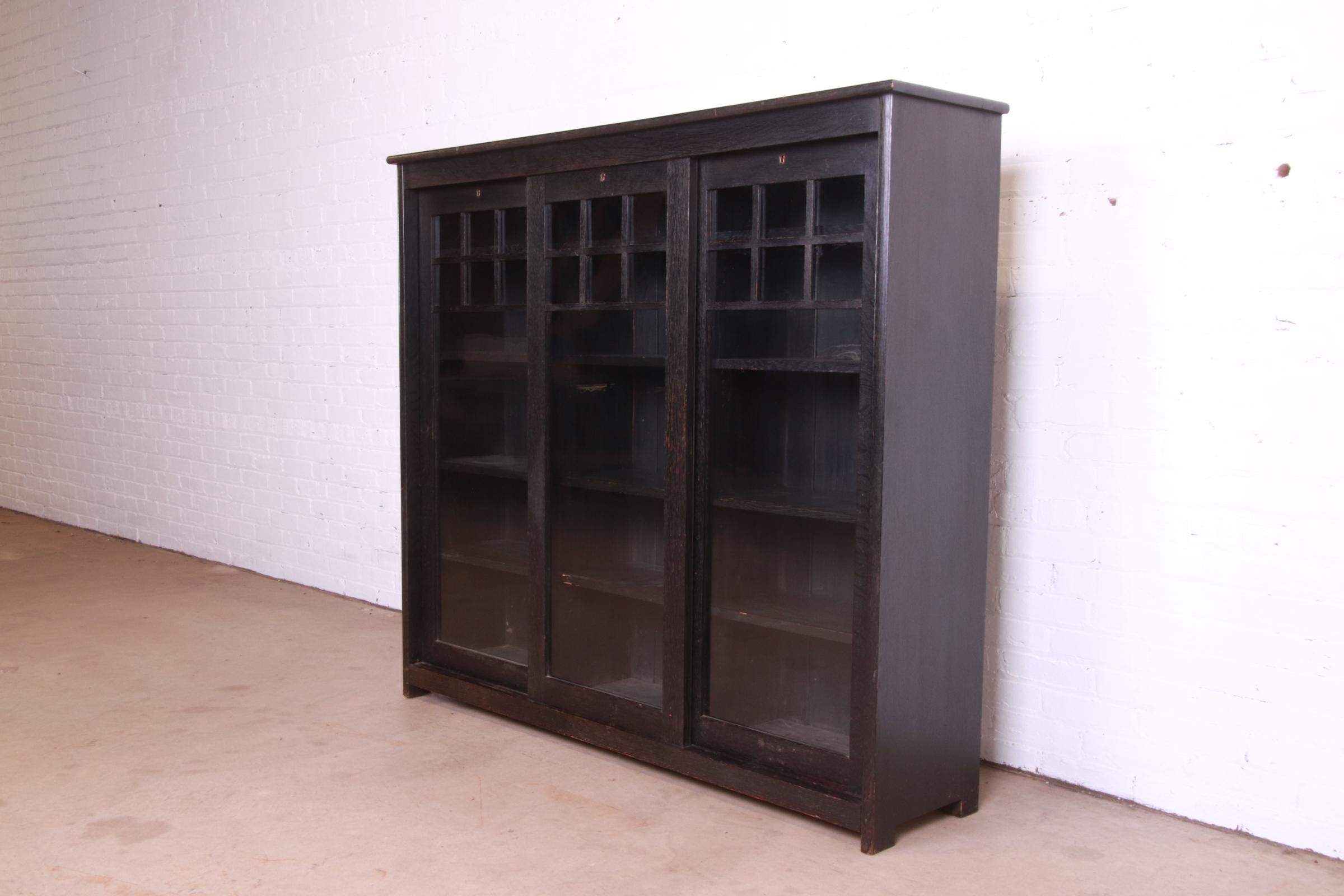 A beautiful antique Mission oak Arts & Crafts triple bookcase

In the manner of Stickley

USA, Circa 1900

Fumed dark quarter sawn oak, with sliding mullioned glass front doors.

Measures: 60.75
