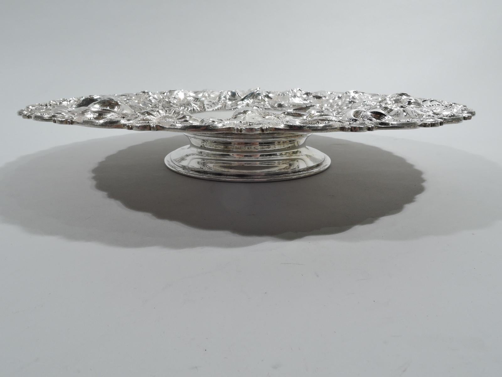 Rose sterling silver cake plate. Made by the Stieff Company in Baltimore in 1916. Round and plain well and wide shoulder with repousse flowers—including plenty of big blooming roses—on stippled ground. Rim has alternating applied scrolls and scallop