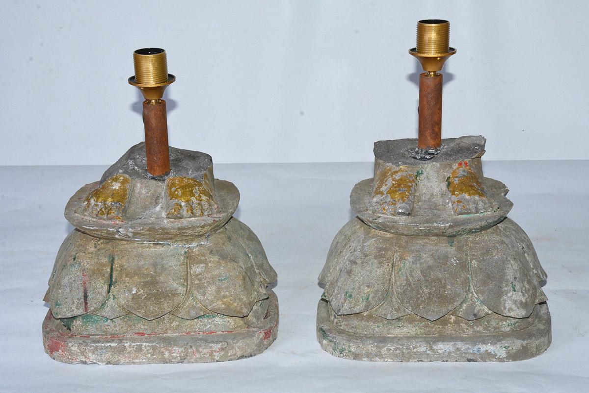 Highly unique and special, a pair of similar but not identical antique rustic organic lamps are composed of two carved stone bases made from architectural elements. Gold leafed feet that were probably fragments from Buddha statues atop lotus flower