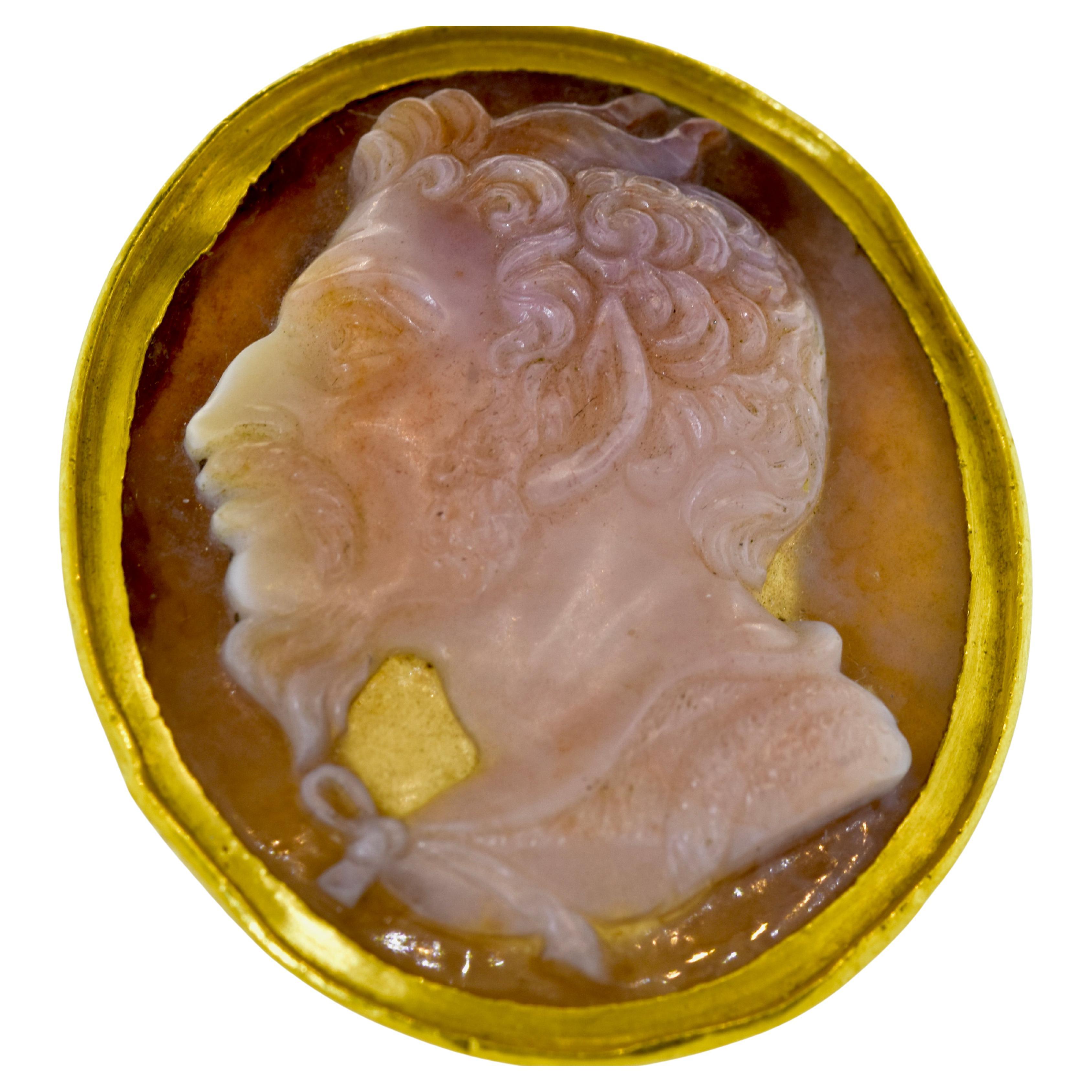 Superbly carved agate, 17th/18th century, and possibly earlier, depicting a mythological male figure with horns, extravagant ear and rugged nose.  This, in turn, is set in an early 20th century ring mounting consisting of 22K yellow gold, unmarked,