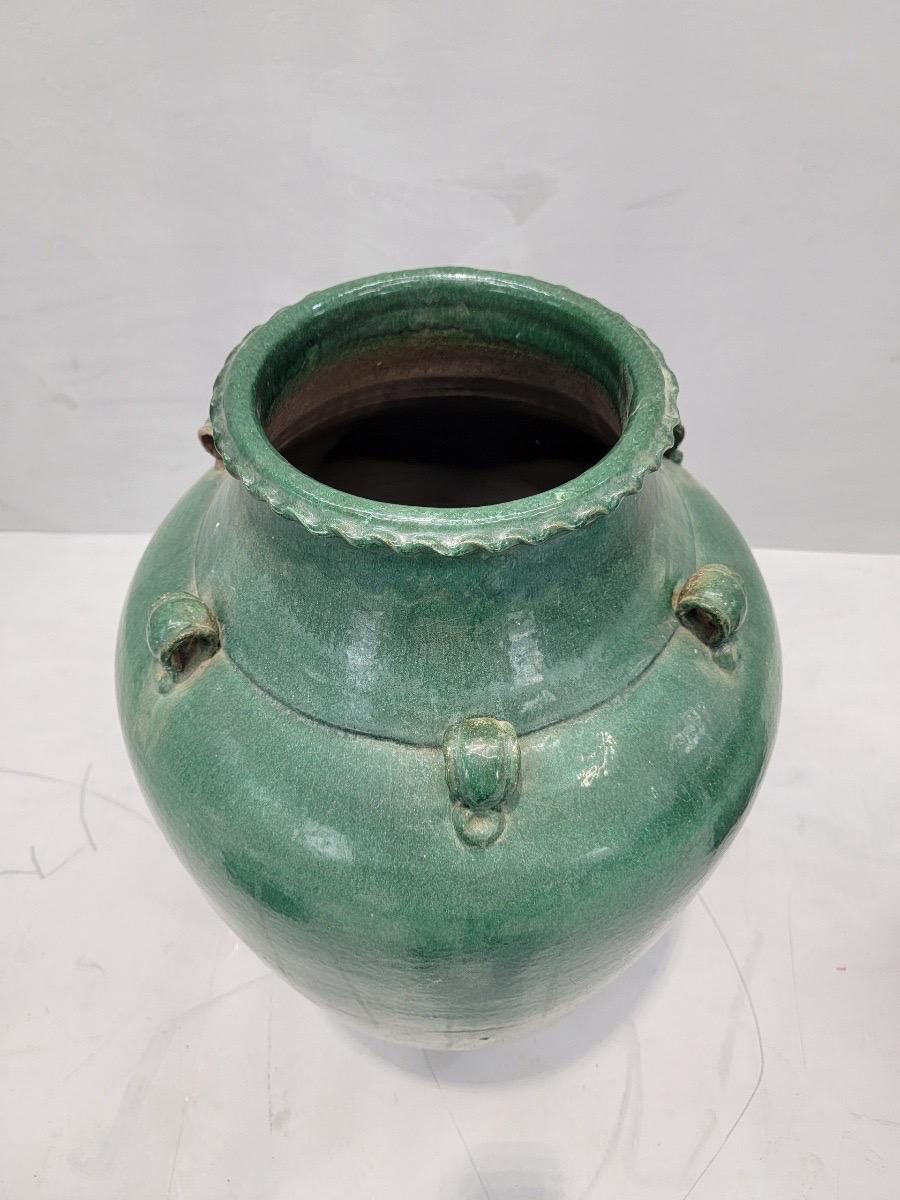 Antique Stoneware Large Green-Glazed Mataban Jar

This large antique Chinese urn/jar has six small handles and a shiny green surface. Its shiny green glaze would make it great for a minimalist and/or naturalist space. Once crafted as an overseas