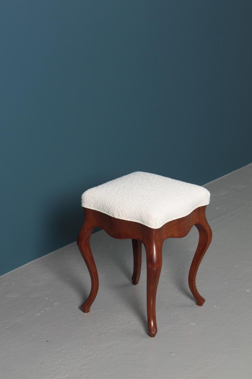 Stool in mahogany with in new bouclé seat, designed and made in Denmark, circa 1910.