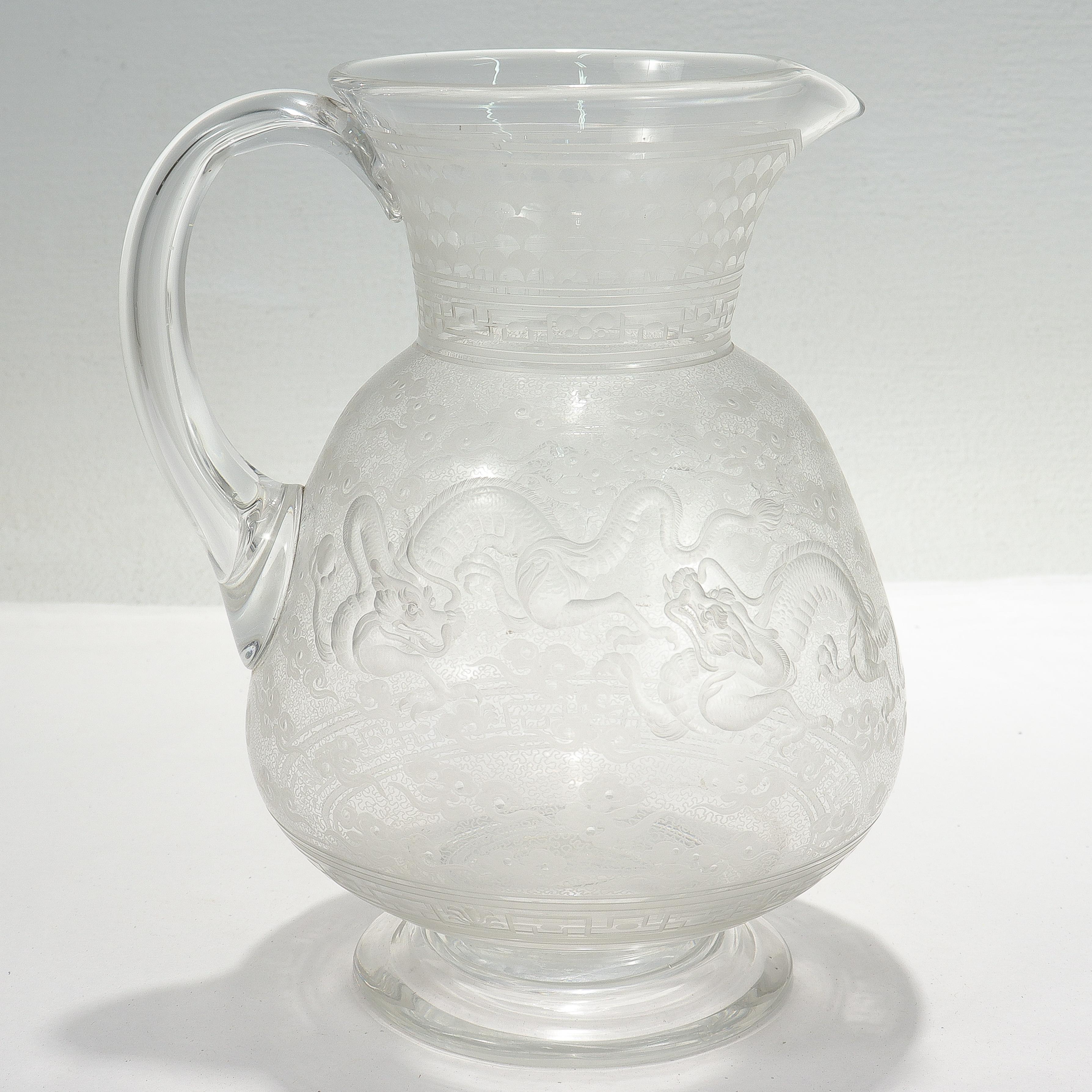 A fine antique etched & engraved glass water pitcher.

Attributed to Frederick Kny and Webb.

Each side with engraved & etched designs of 2 Chinese dragons chasing a pearl amongst clouds. 

A possibly related decanter is held in the Victoria and