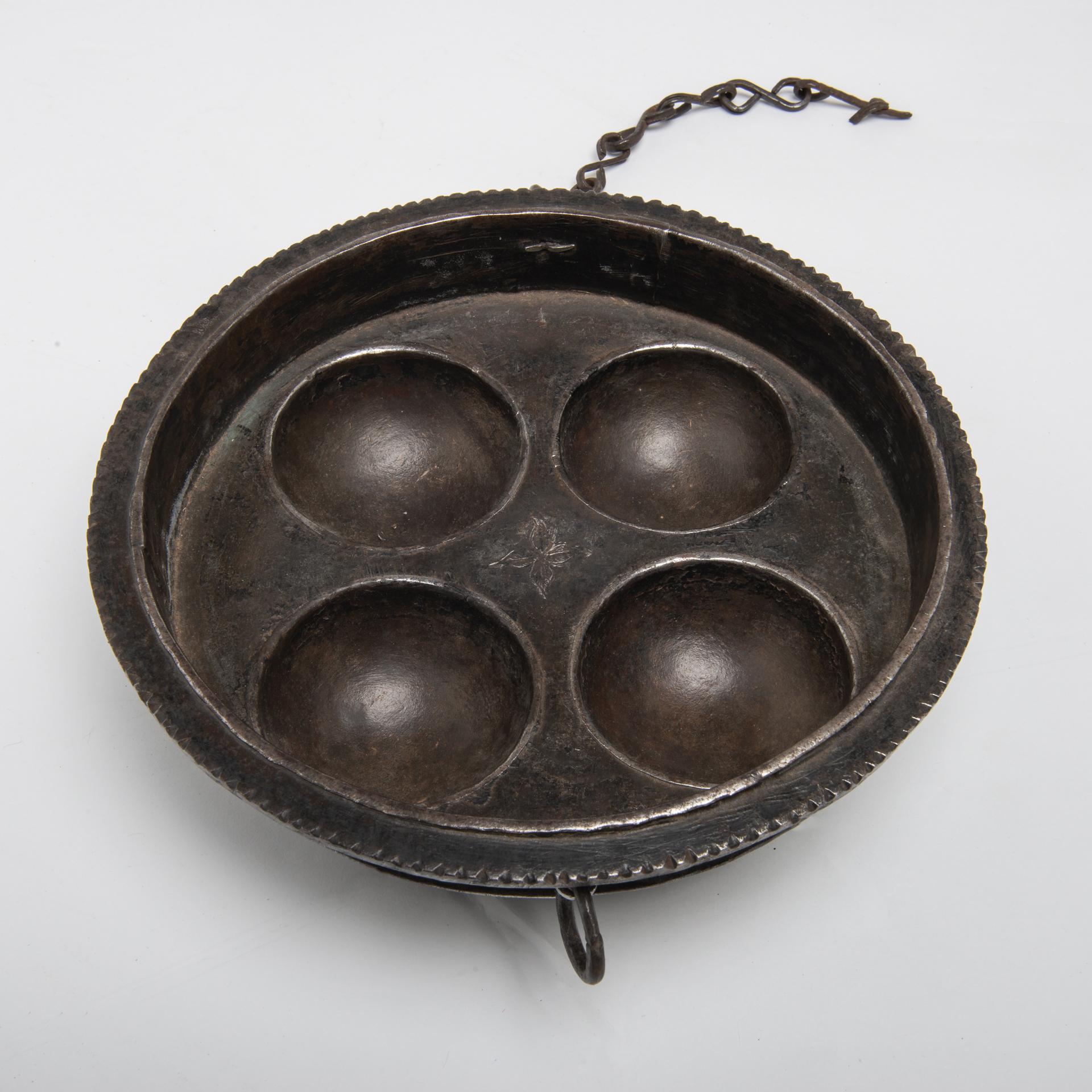 O/292-6-  A friend of mine found this iron pot in Tibet: it's a strange particular pot in heavy iron with round compartments.
The chain was used to hang it when not in use.
Now how to use it ? To make pancakes or round cakes ? It's heavy and sturdy.