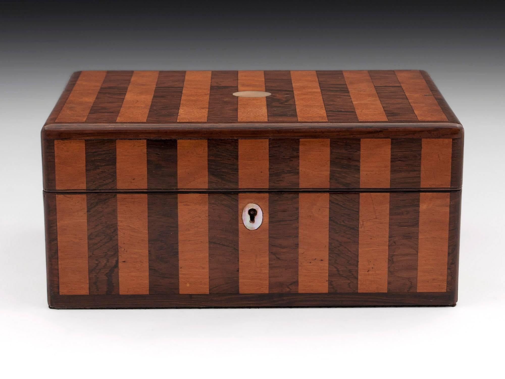 Antique jewellery box veneered in mahogany and satinwood stripes running from top to front of the box with mother-of-pearl escutcheons.

The interior is lined in navy blue paper with cushioned blue velvet.

This antique box comes with a fully