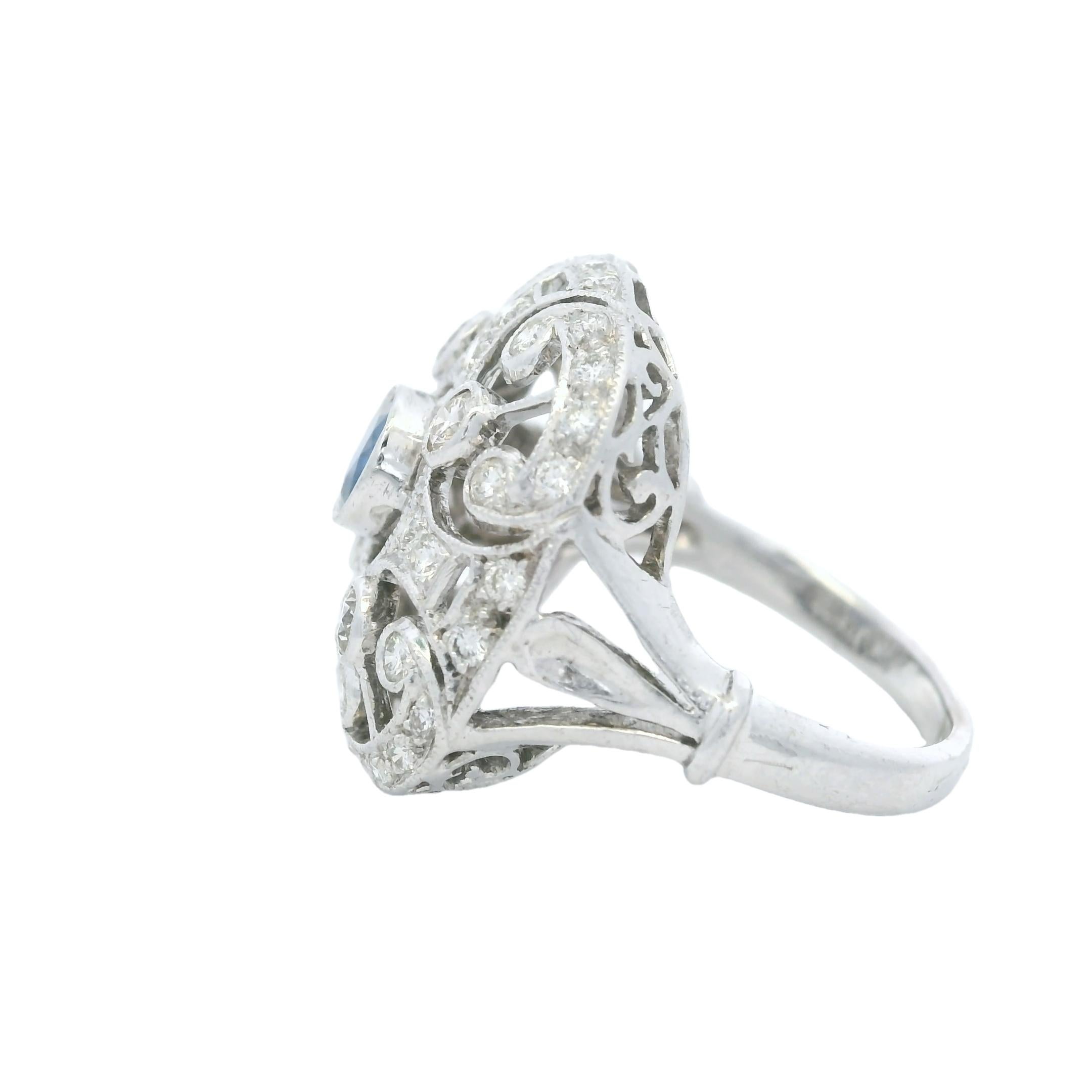 A romantic fusion of vintage charm and refined craftsmanship, this 14K white gold filigree ring features a captivating old-world design. At its center is a bezel-set natural sapphire weighing approximately 0.20 carats, surrounded by intricate