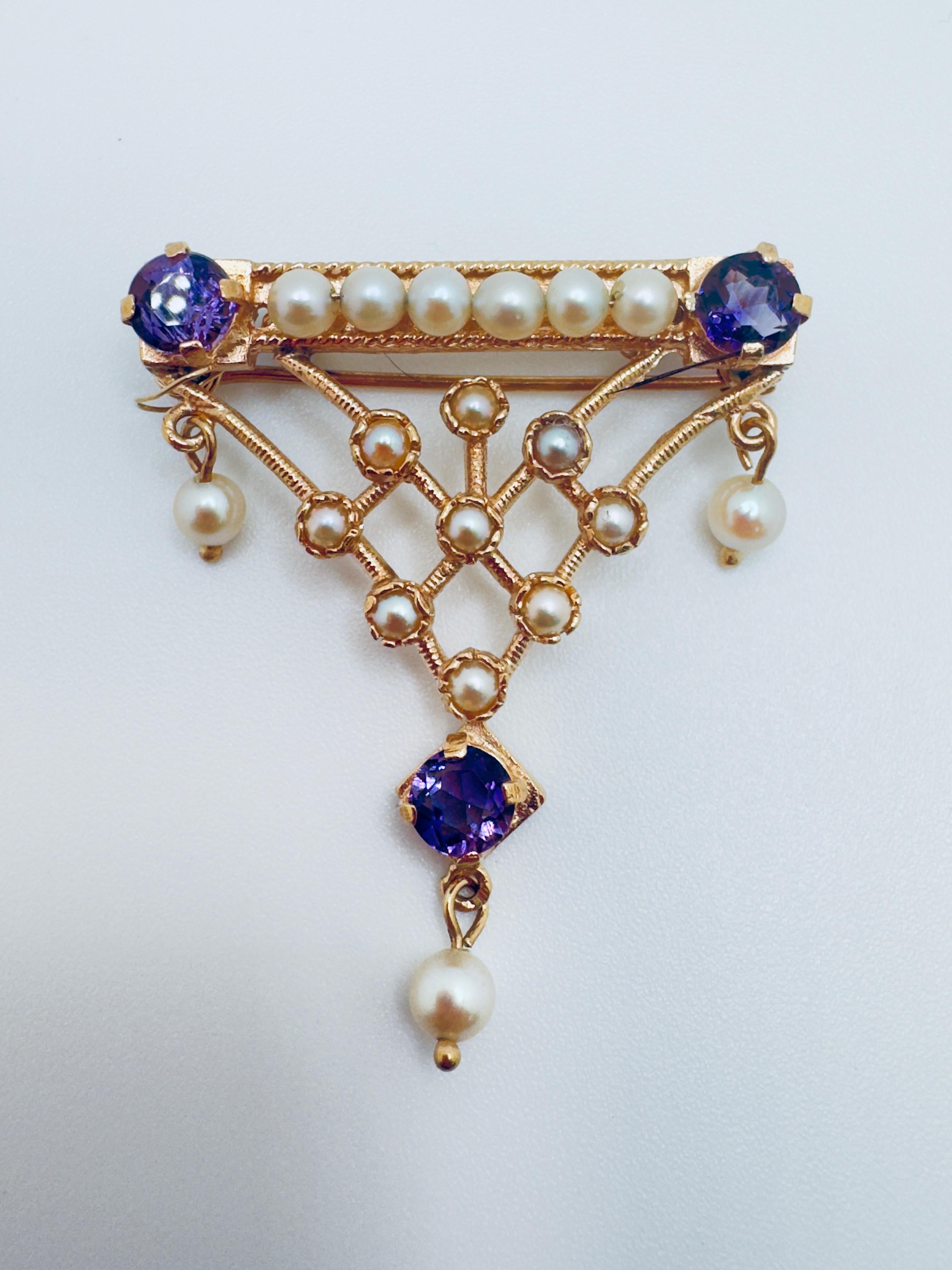Este delicado broche de estilo antiguo está bellamente elaborado en oro amarillo de 14 quilates, combinando la elegancia atemporal con un diseño refinado. La pieza central presenta tres piedras redondas de amatista, cada una de aproximadamente 4,5