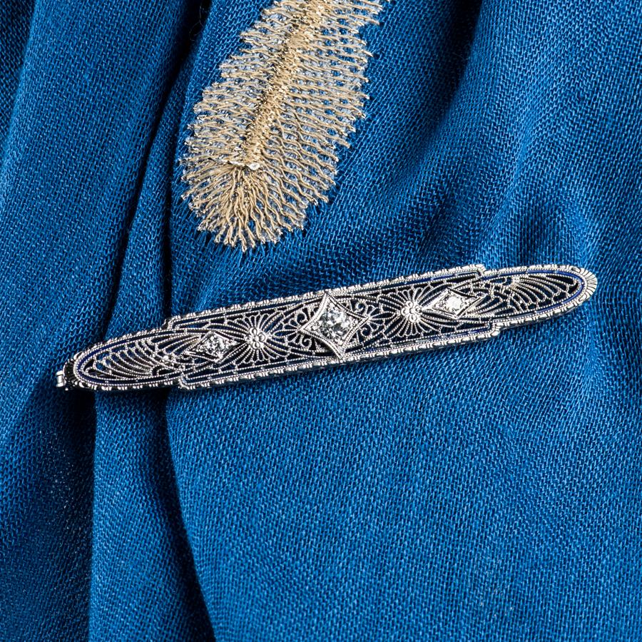 Antique style brooch/pin with 3 European cut diamonds weighing approximately 0.45ct total and a thin border of blue enamel set in 14k white gold. Side diamonds measure approximately 2.7mm, center diamond measures approximately 4.3mm.