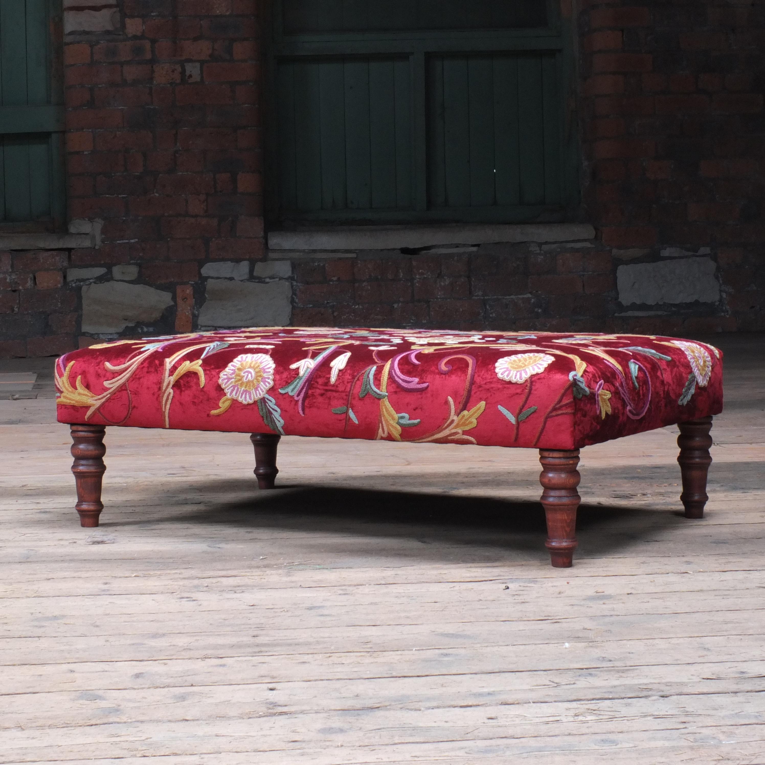 A large footstool covered in Indian hand embroidered crewelwork fabric. 100% wool stitched into a red velvet base fabric. Very nice vibrant colours throughout and quite the statement piece.

If you would like a footstool making in a different