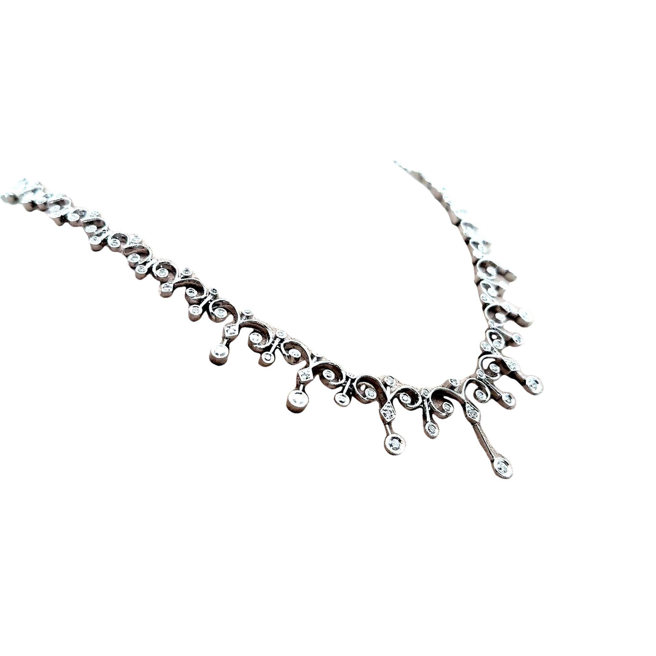 Questa squisita collana di ispirazione antica presenta una serie di diamanti bianchi a taglio rotondo per un totale di 3,16 carati. Realizzata in oro bianco 18 carati, la collana presenta un intricato disegno con delicate volute, popolari alla fine