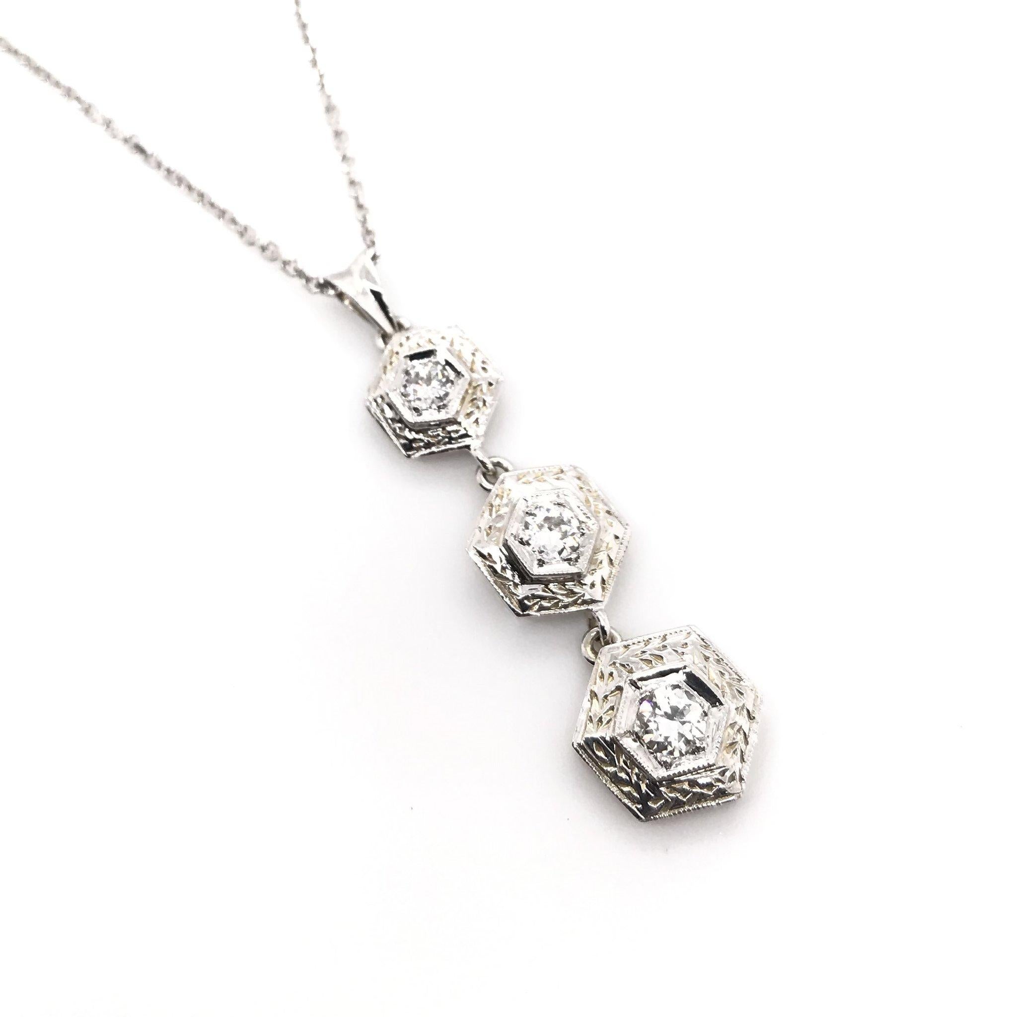 This beautiful diamond necklace is a contemporary piece, crafted in an Art Deco antique style. The 14K white gold pendant features a trinity drop style with extensive engravings, milgrain accents, and three sparkling diamond accents. The necklace's