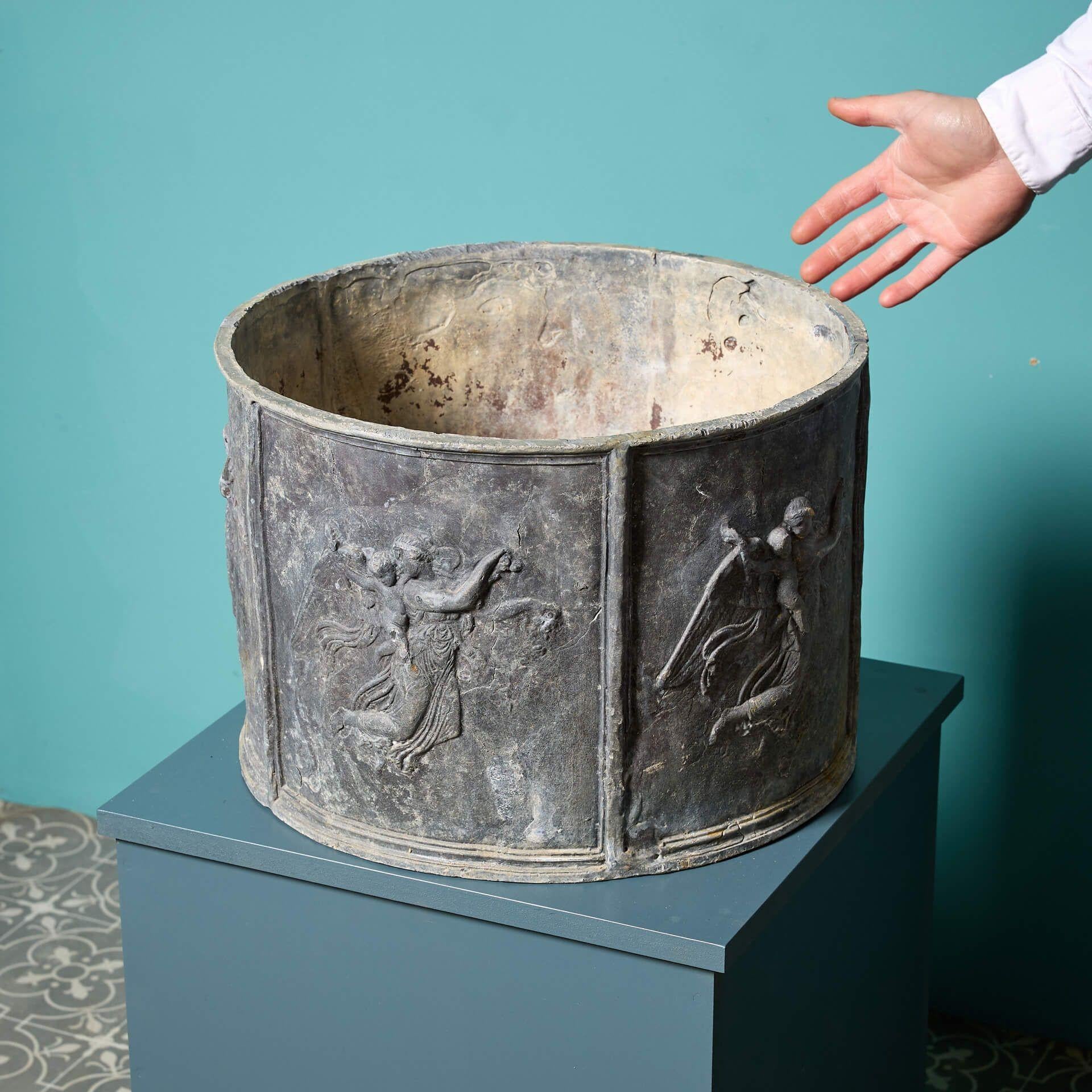 An antique style English lead garden planter in a circular form.


Showcasing characterful weathering, this lead planter dates from the mid 20th century and has an attractive timeworn appeal.

The front is decorated with five panels housing a winged