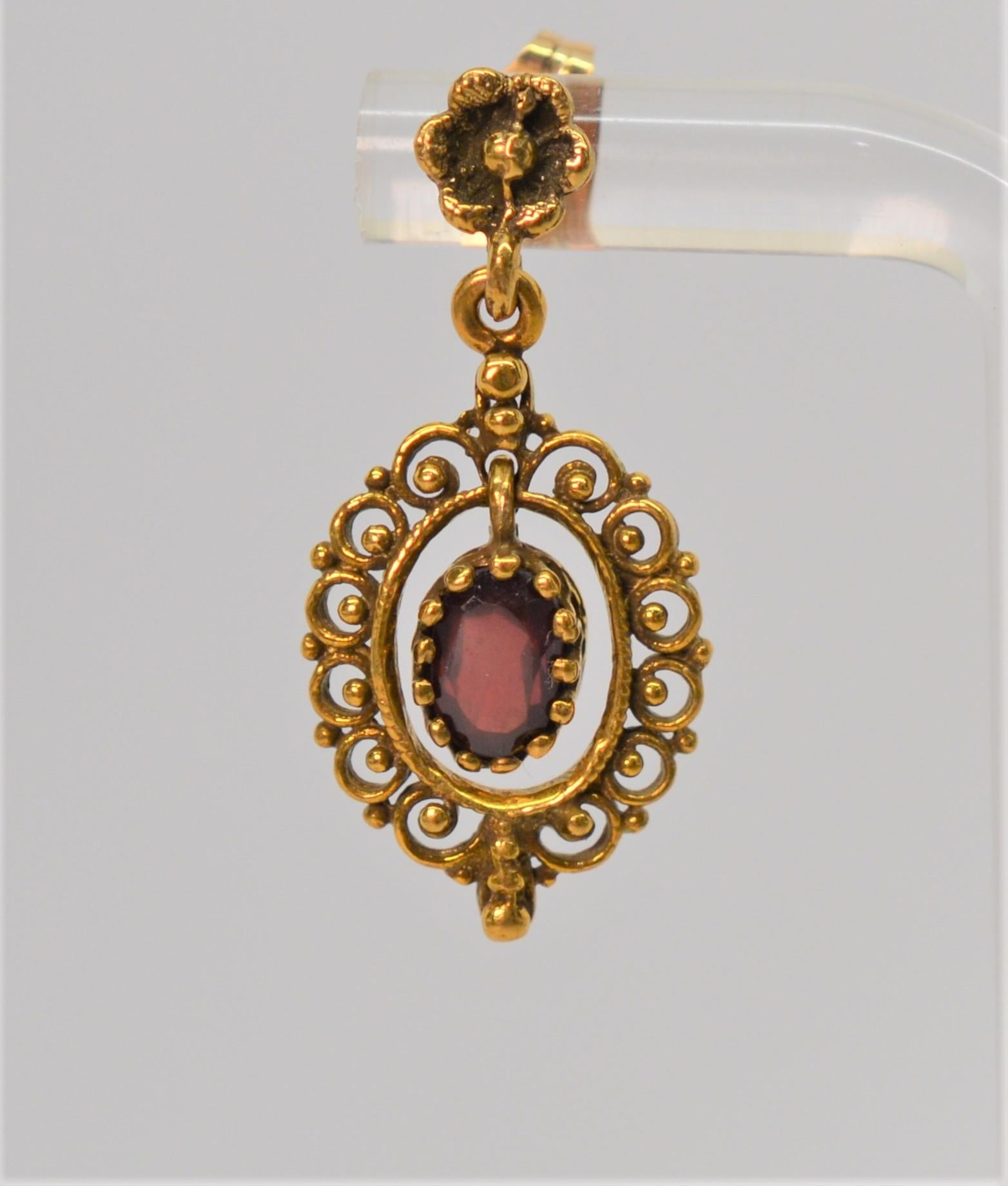 Deep rich red oval garnets in a dainty frame of 14 Karat gold with an antique style patina create this classic dangle earring pair. Post closures for pieced ears, these earrings measure one inch in length from top post to end. In gift box. 
