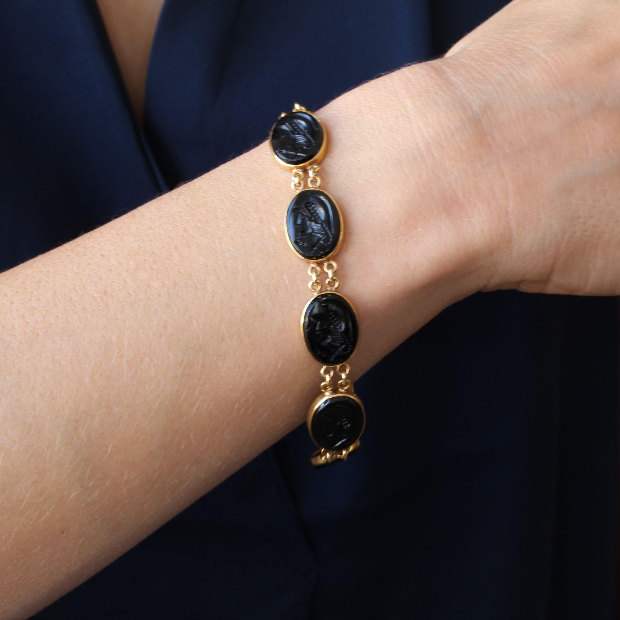 Armband aus 14 Karat Gelbgold, Muschelpunze.
Dieses Armband aus zweiter Hand besteht aus Intaglios auf Glaspaste, die das Profil eines behelmten Kriegers in geschlossener Fassung darstellen. Sie sind voneinander getrennt und durch eine Doppelkette