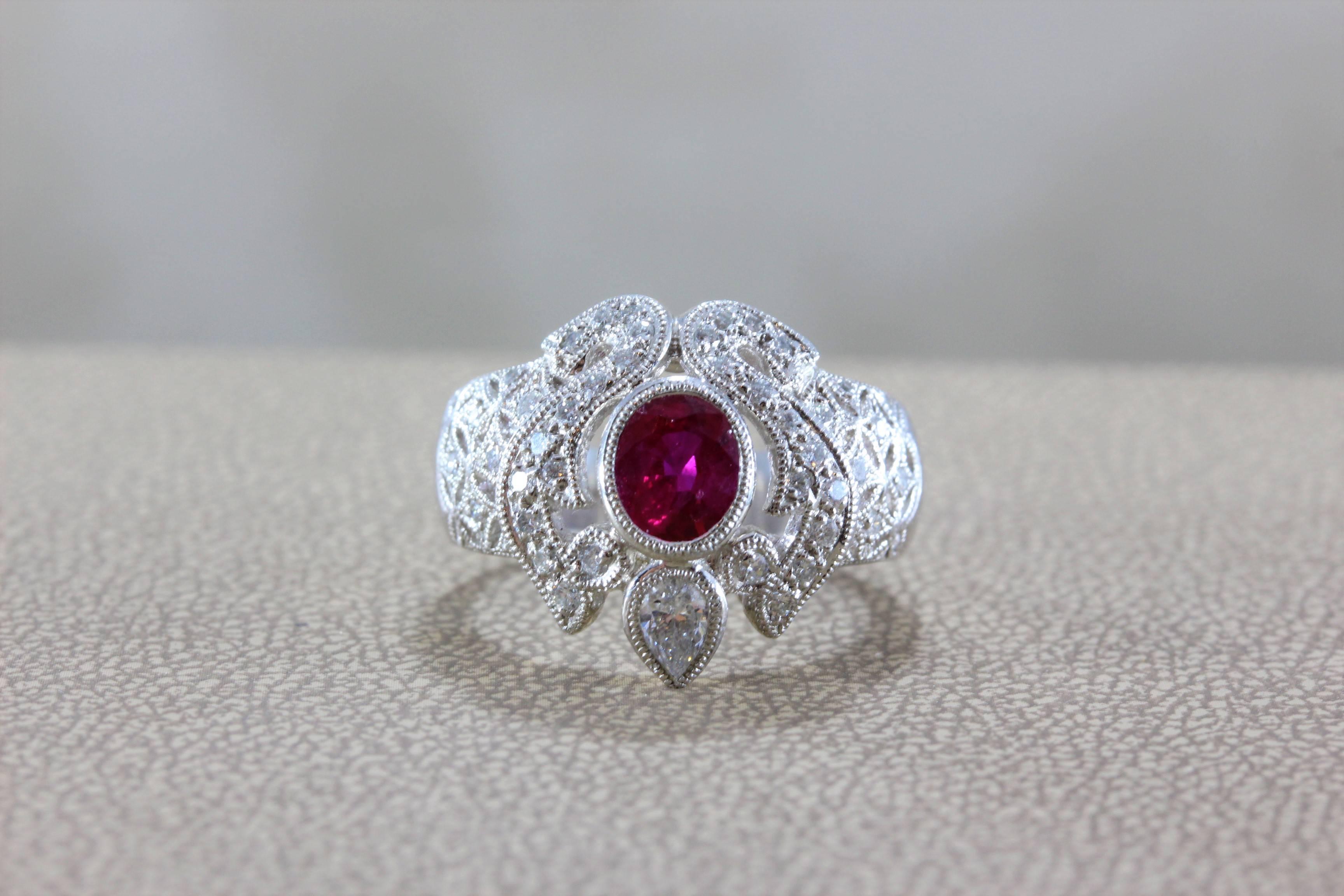 Un bellissimo anello in platino con un rubino rosso vivido di forma ovale, del peso di 0,92 carati, che crediamo abbia un'origine birmana. Un diamante più grande a forma di pera e dei tondi accentuano la pietra centrale, incastonata in platino con