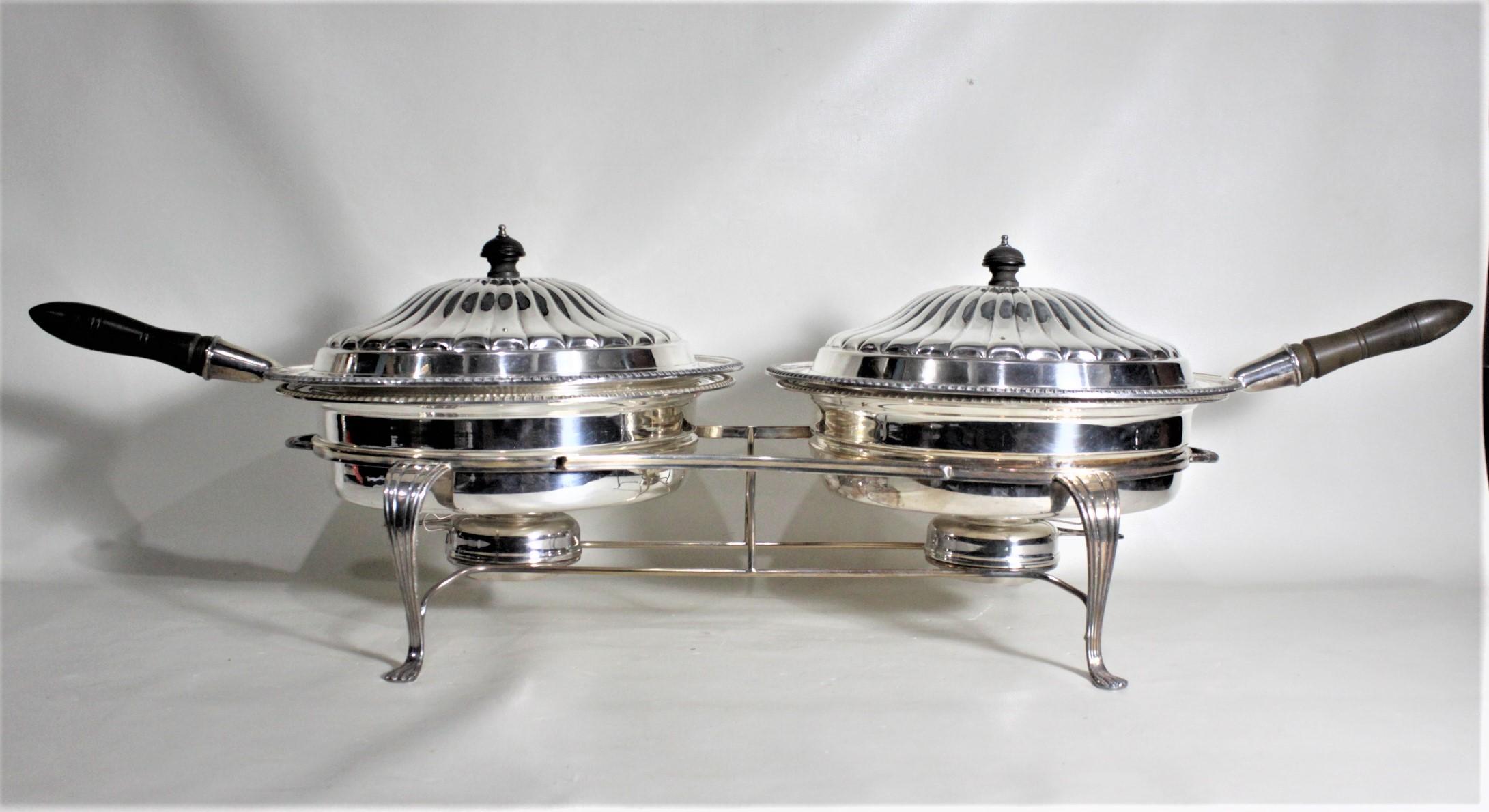 This silver plated double warm food server was made in England during the 1960s in the Victorian style. This serving set comes complete with lined and lidded serving pots with turned wooden handles and finials and a sturdy serving stand with two