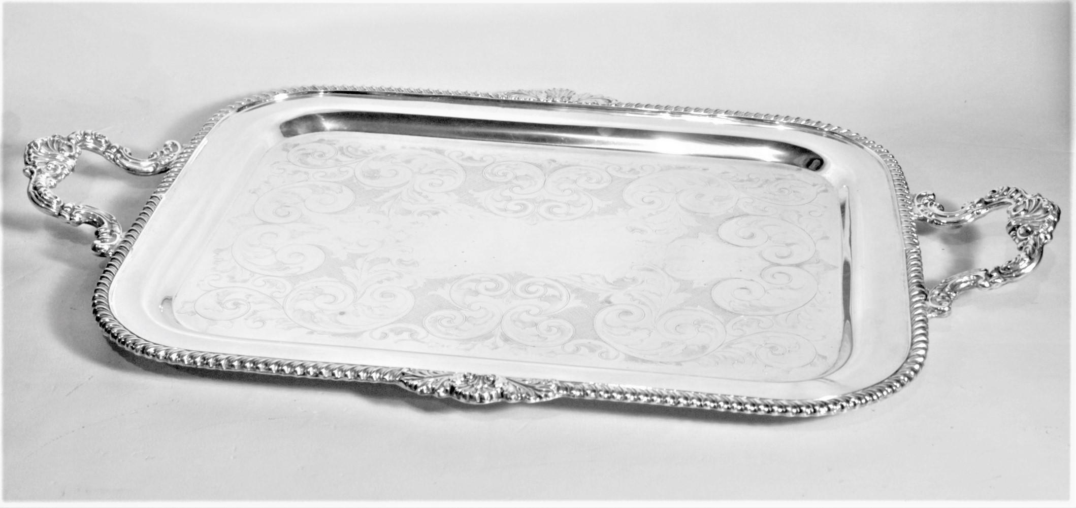 This rectangular antique styled silver plated serving tray was made in Canada by Marlboro Plate in a Victorian English style. The tray has a rope patterned surround with accenting fan decoration on either side and very ornately cast applied handles.