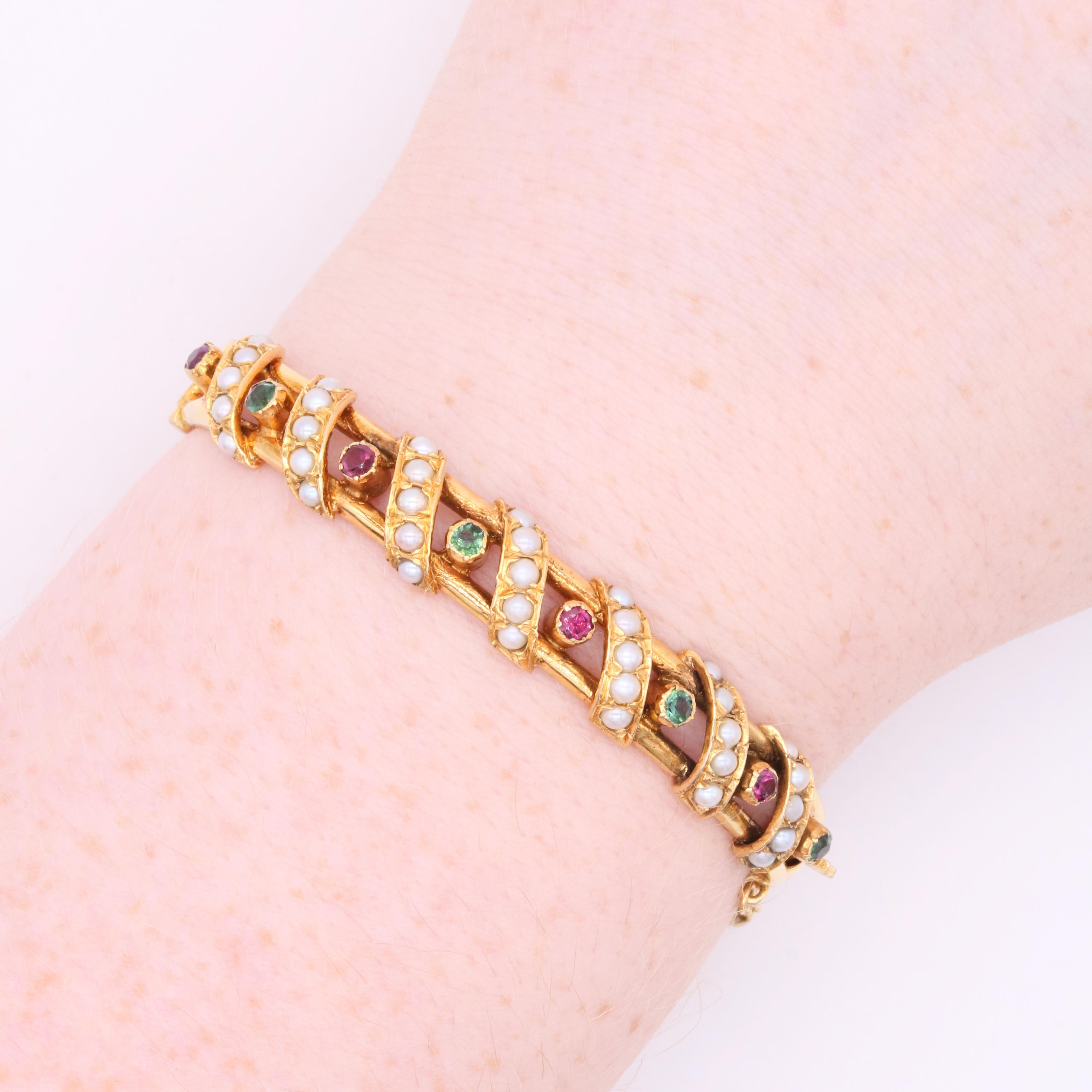 An antique rhodolite garnet, peridot, and pearl bracelet in yellow gold, comprising four rhodolite garnets, four peridots and thirty-five seed pearls, set in 18 karat yellow gold, to a bracelet of 18 karat yellow gold. 

The bracelet is crafted