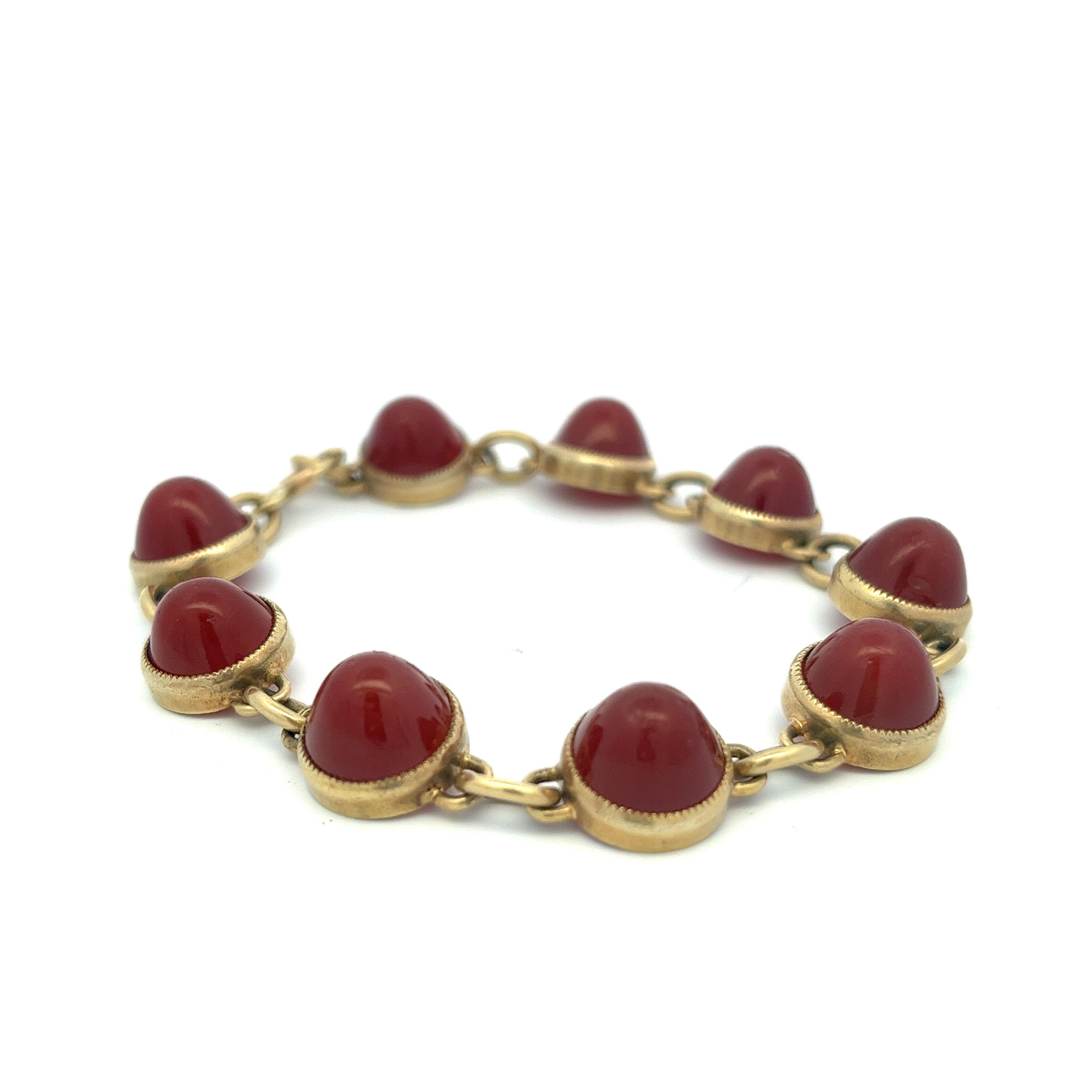 This exquisite bracelet showcases a sequence of nine carnelian cabochons, each featuring a sugarloaf cut that resembles elegant gumdrops adorning the wrist. The cabochons are meticulously bezel-set, harmoniously linked by 14-karat gold chains with a