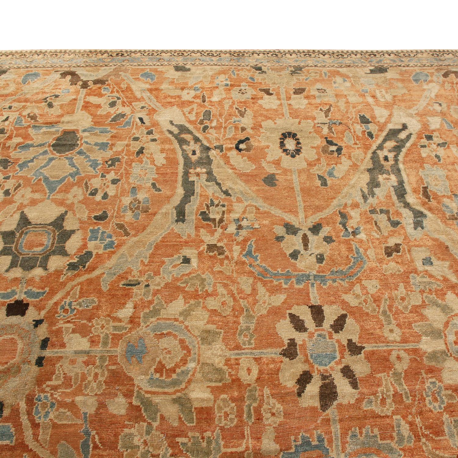 Hand knotted in high-quality wool originating from Persia between 1880-1890, this antique Sultanabad Persian rug lends spacious warmth and elegance to a space, enjoying a rich combination of vibrant orange, regal navy blue, and beige colorways
