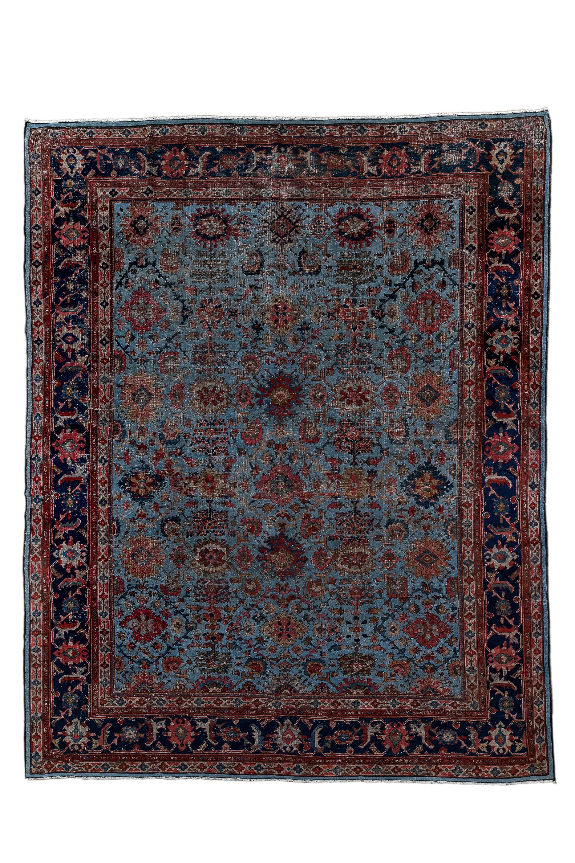 This modestly woven room size carpet shows a medium blue field with a five column, much modified Harshang design with symmetrical rosettes replacing ragged palmettes. Details in darker blue, rust, green and creamy beige.  Dark blue strip style