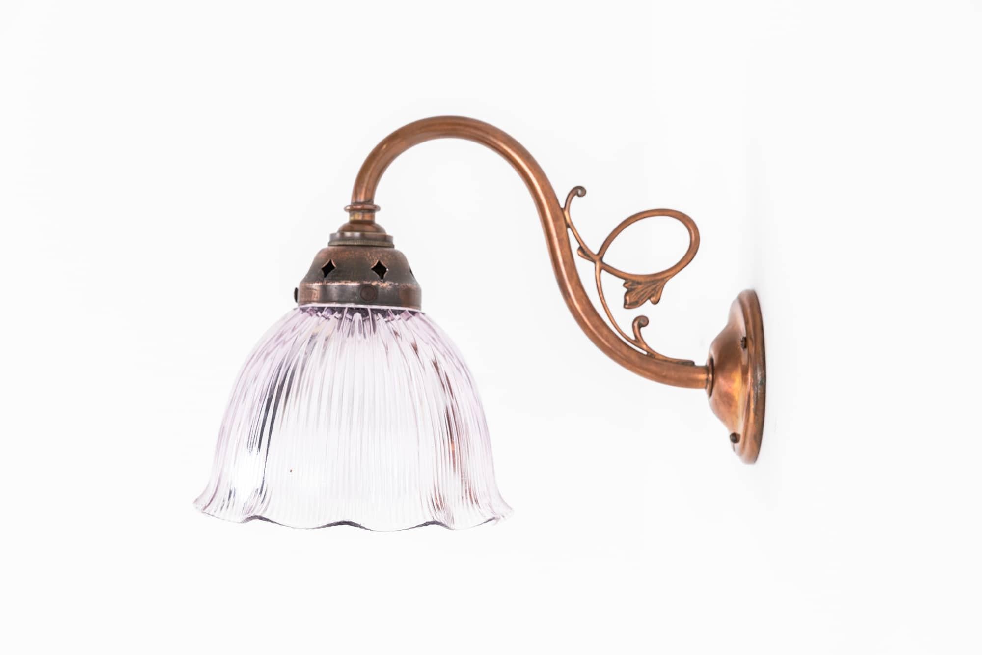 

A beautiful diminutive wall sconce made in England by Sunco. c.1930

Constructed from brass with copper plate and cast decorative detail. Complemented by a equally as elegant violet tinted Holophane Stiletto glass shade.

Rewired to connect to