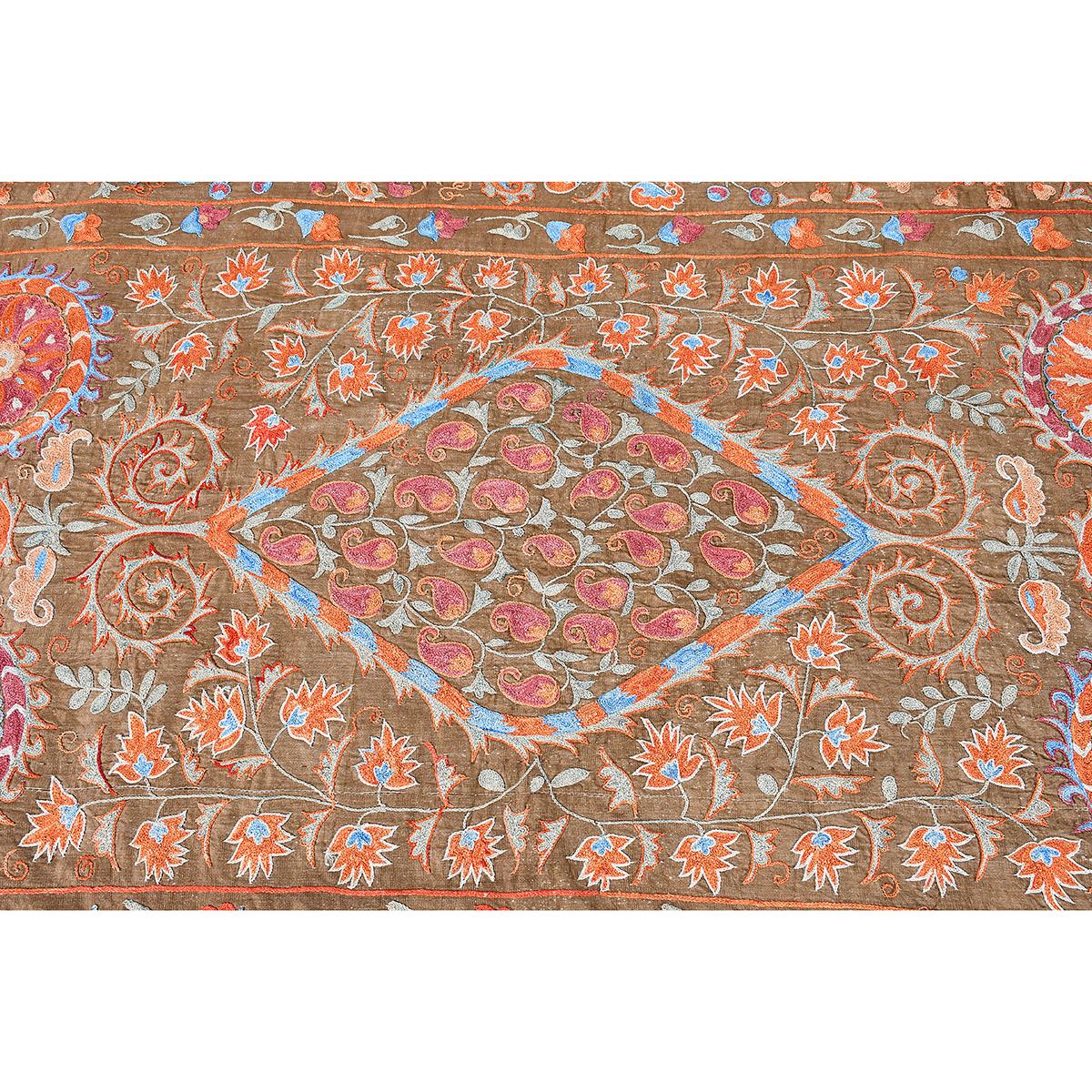 Un bordado suzani de seda sobre fondo marrón. Con un diseño de colores brillantes de flores y bayas. El borde ancho está perfilado por dentro y por fuera por un borde más pequeño de flores enredaderas. Respaldo posterior.