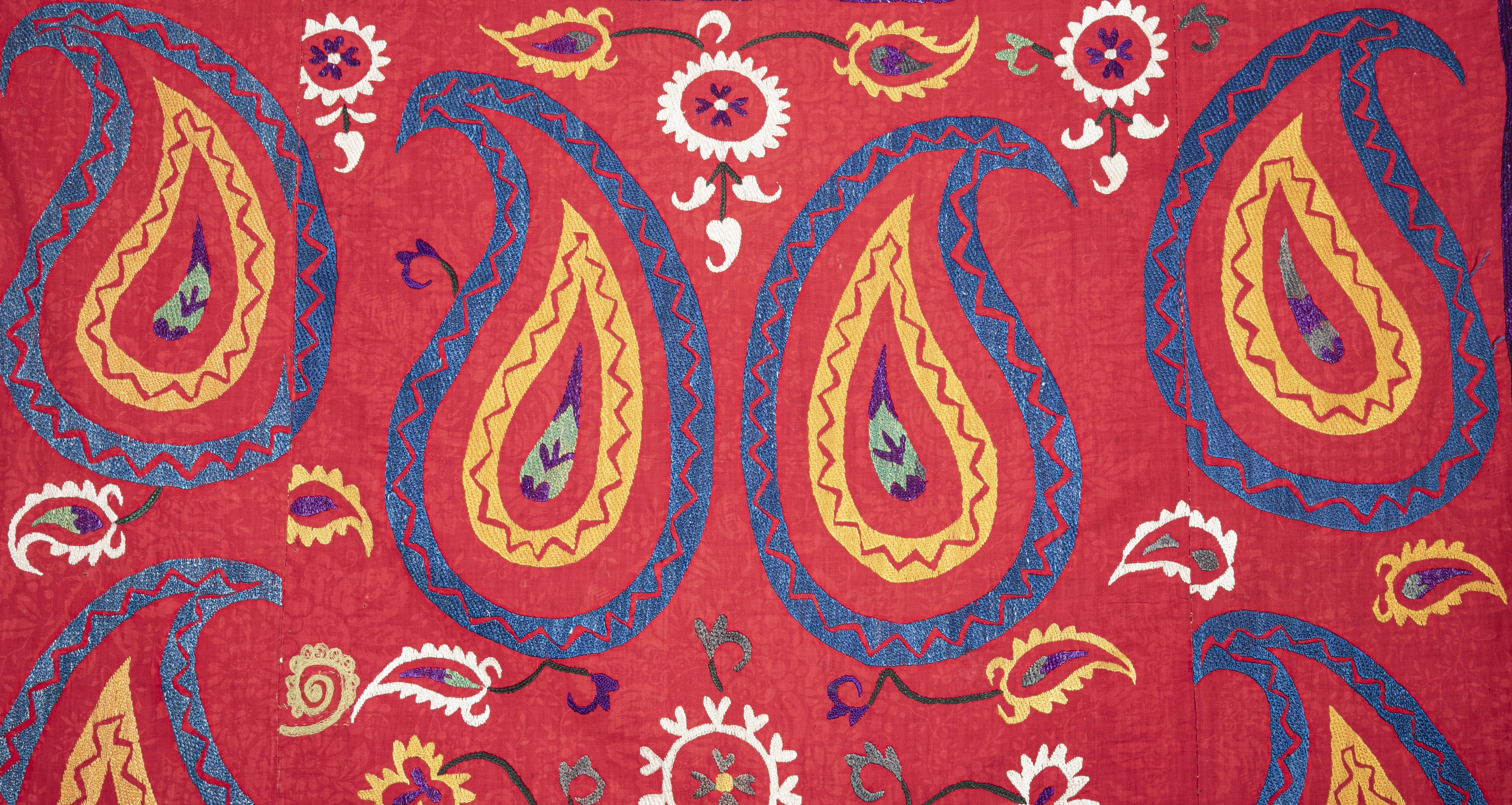 A red ground example to Uzbek suzanis embroidered in silk on a Russian printed cotton trade cloth. Border are missing.