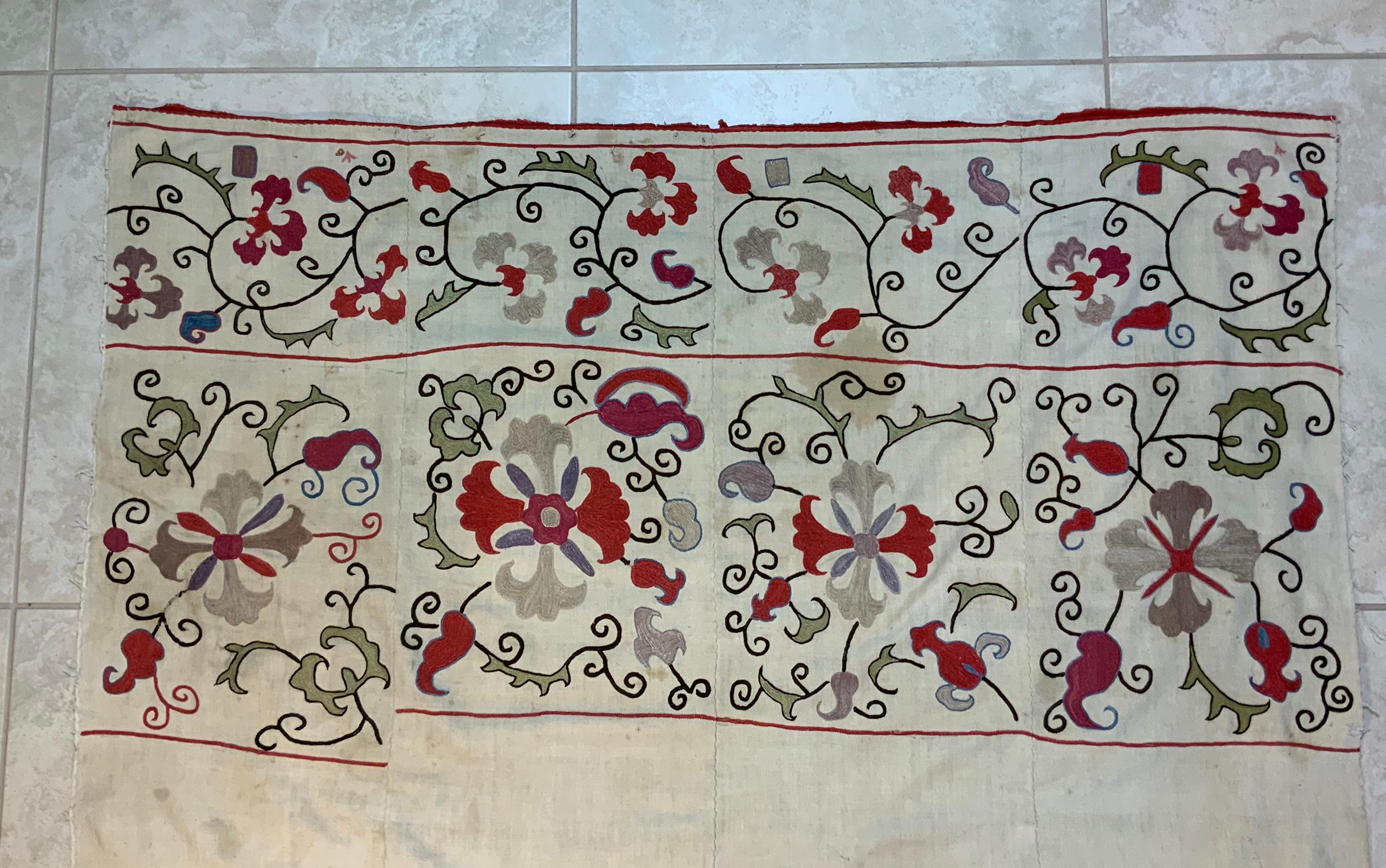 Antique Suzani fragment made of hand embroidery intricate scrolling vines and flowers motifs on a handwoven cotton background.
This piece has some spots and fading areas, some small tears, some oxidization due to age but still has a good structural