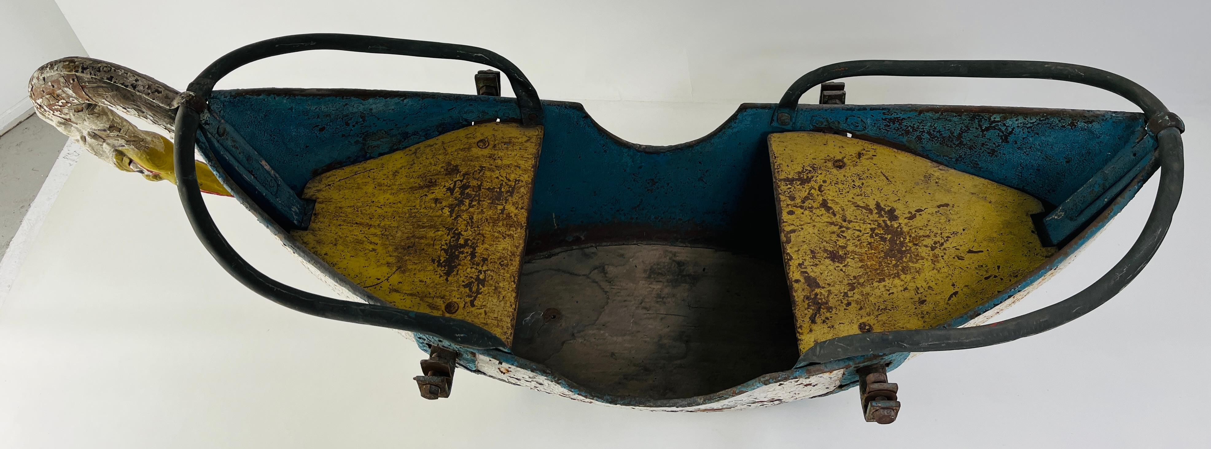 A beautifully timeworn children’s ride-on toy crafted in the evocative shape of a swan, likely dating back to the early to mid-20th century. With layers of cracked white paint revealing hints of blue beneath, the surface reads like a painted