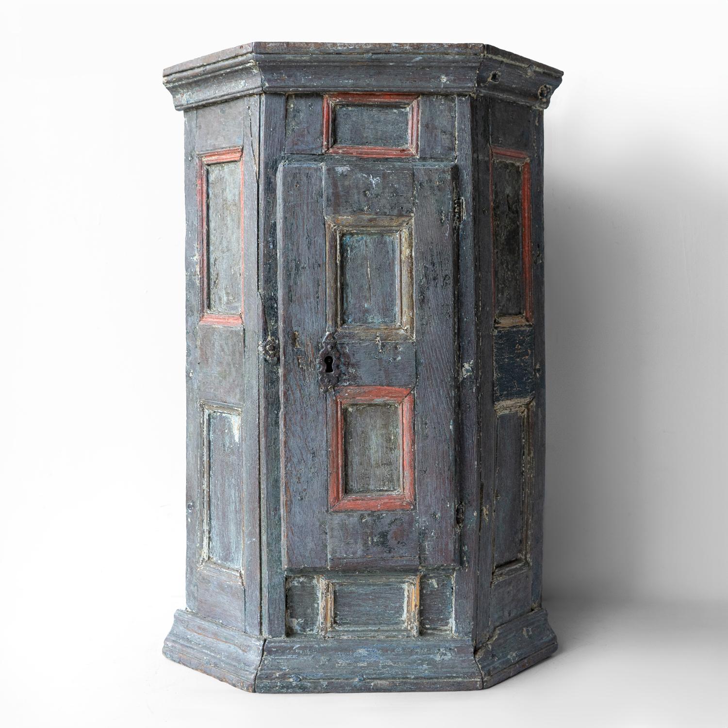 ANTIQUE SWEDISH CORNER CABINET 

A decorative and characterful cabinet with a panelled door and sides and a moulded cornice.

Layers of original and later paint, which has worn in places paint a deep blue/grey with red accents. 

Could be wall