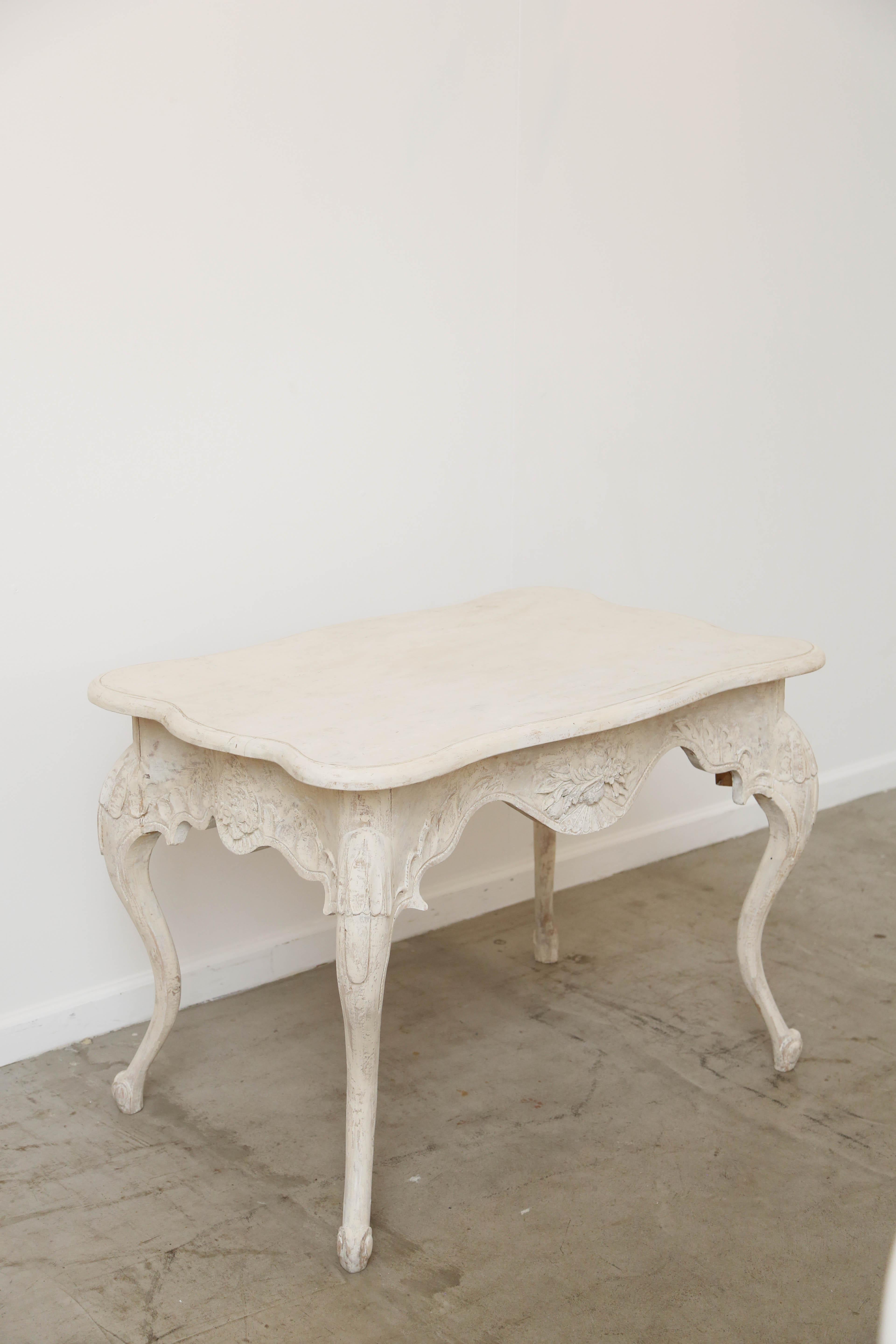 A very elegant antique Swedish Baroque style painted table, with lovely cartouche carving on the apron and leaves carved top each cabriole leg, carved hoof foot on each leg. Top is curved and shaped with a simple semi round edge. Swedish white-cream