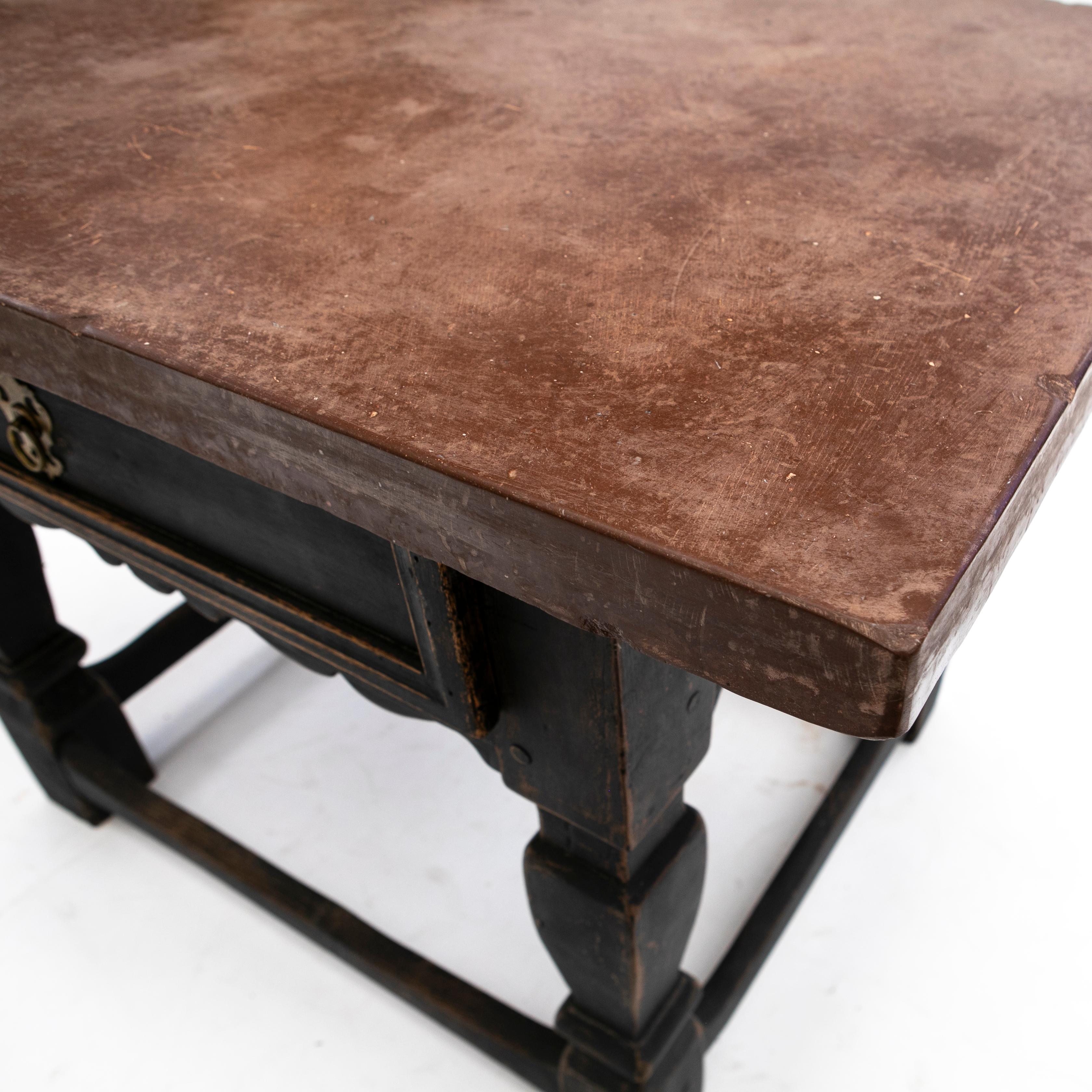 A Swedish baroque table reddish brown Öland limestone top (5 cm. thick).
Black painted oak frame featuring one large drawer with room divider. Resting on powerful baroque legs joined by foot stretchers with having normal signs of age and use with a