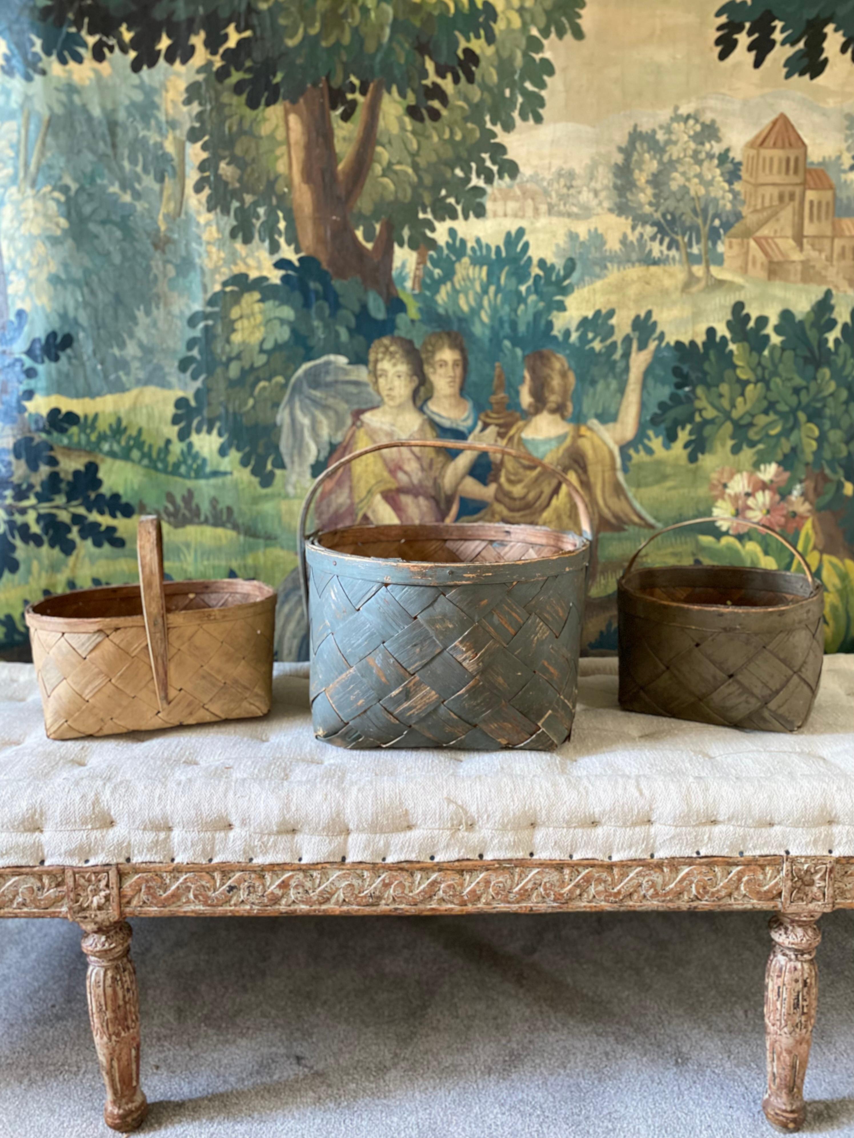 A set of three late 19th century Swedish woven birch baskets all in original paint and offered in good condition - the largest is a round mid teal blue and measures 15” across and 16” high including handle - the two smaller ones are an oval maize
